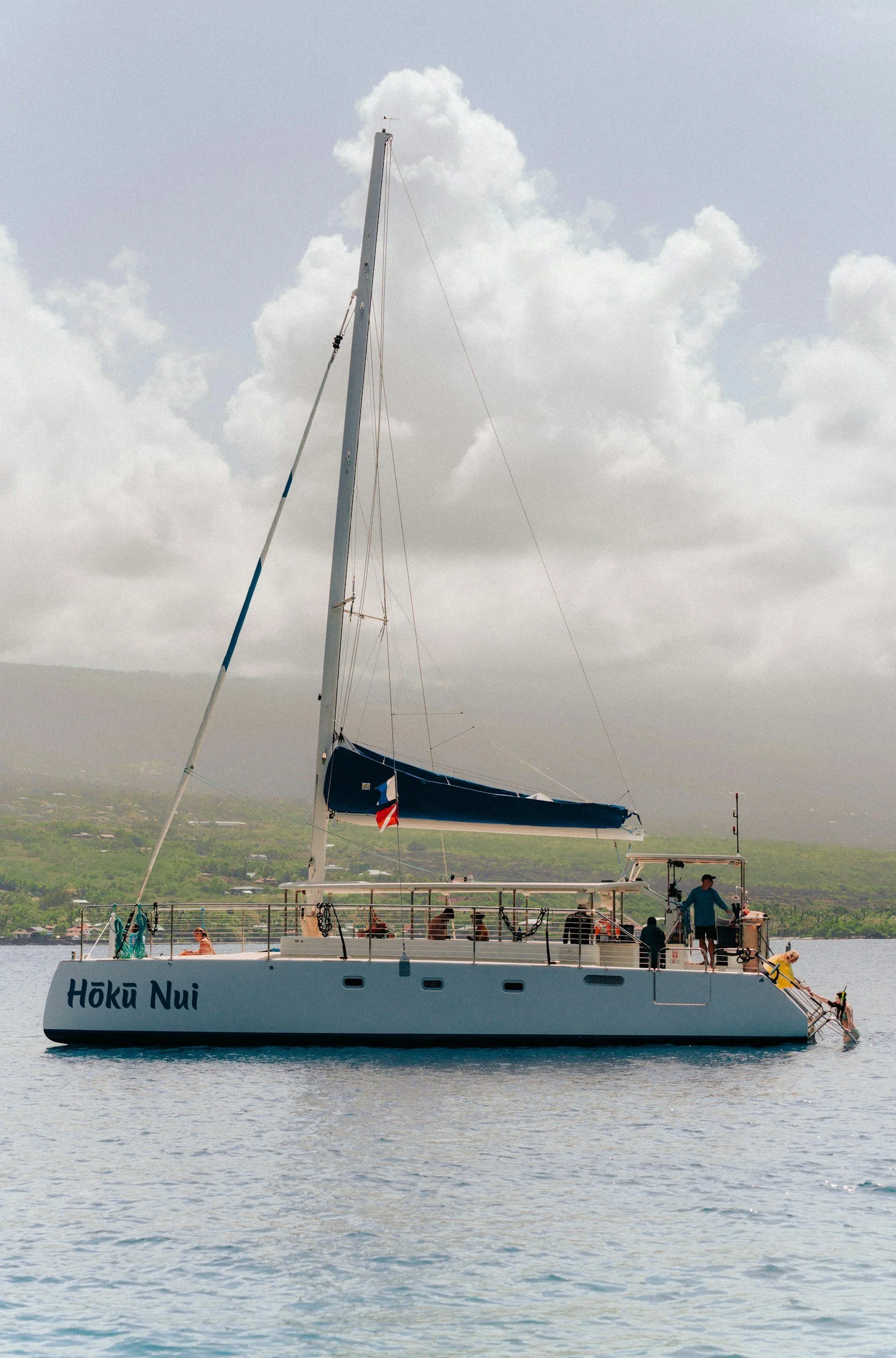 Sailing catamaran with passengers on deck off the coast of Maui, a calm option for families with kids