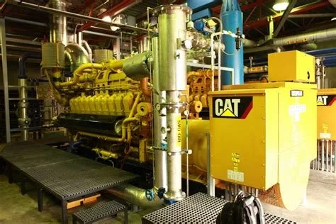 Industrial Power GEN machinery with yellow and green components in a factory setting, including a CAT branded yellow control box.