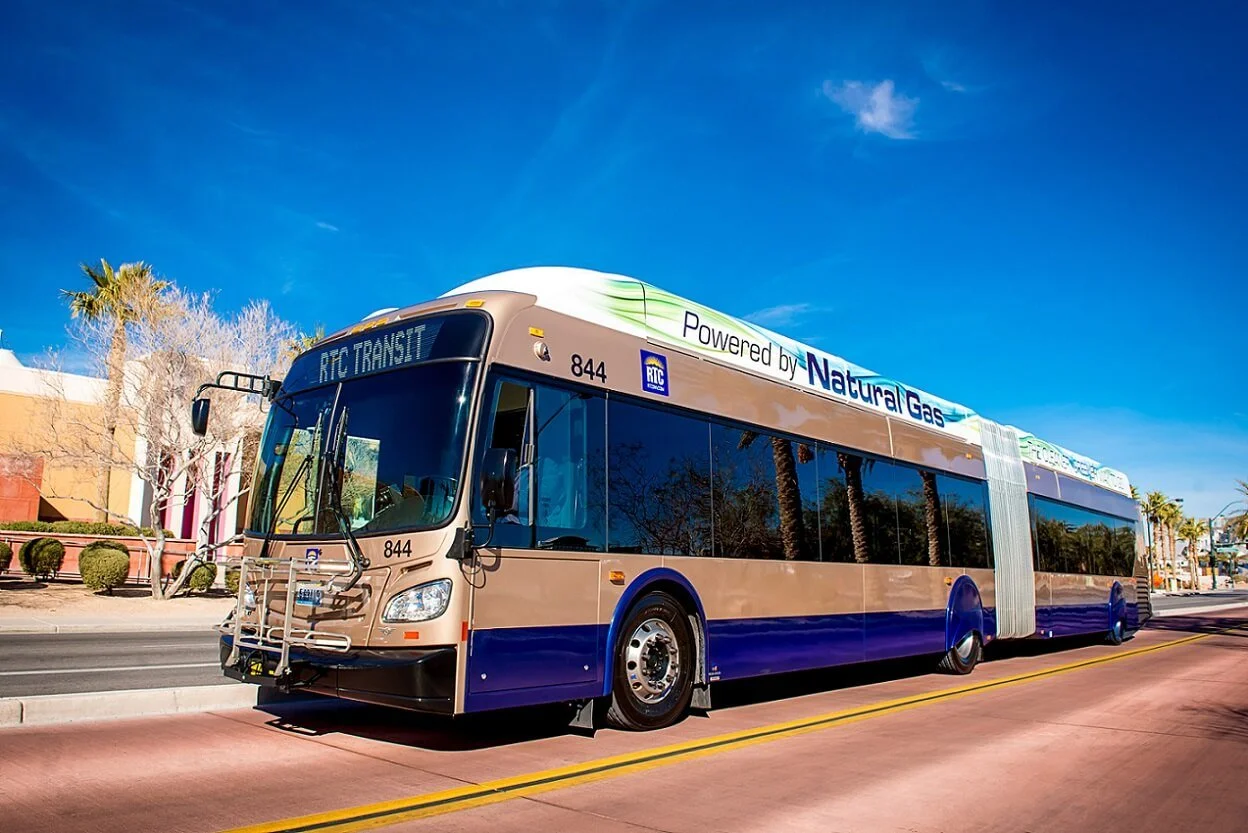 Electric bus powered by natural gas on city street with clear blue sky in background.