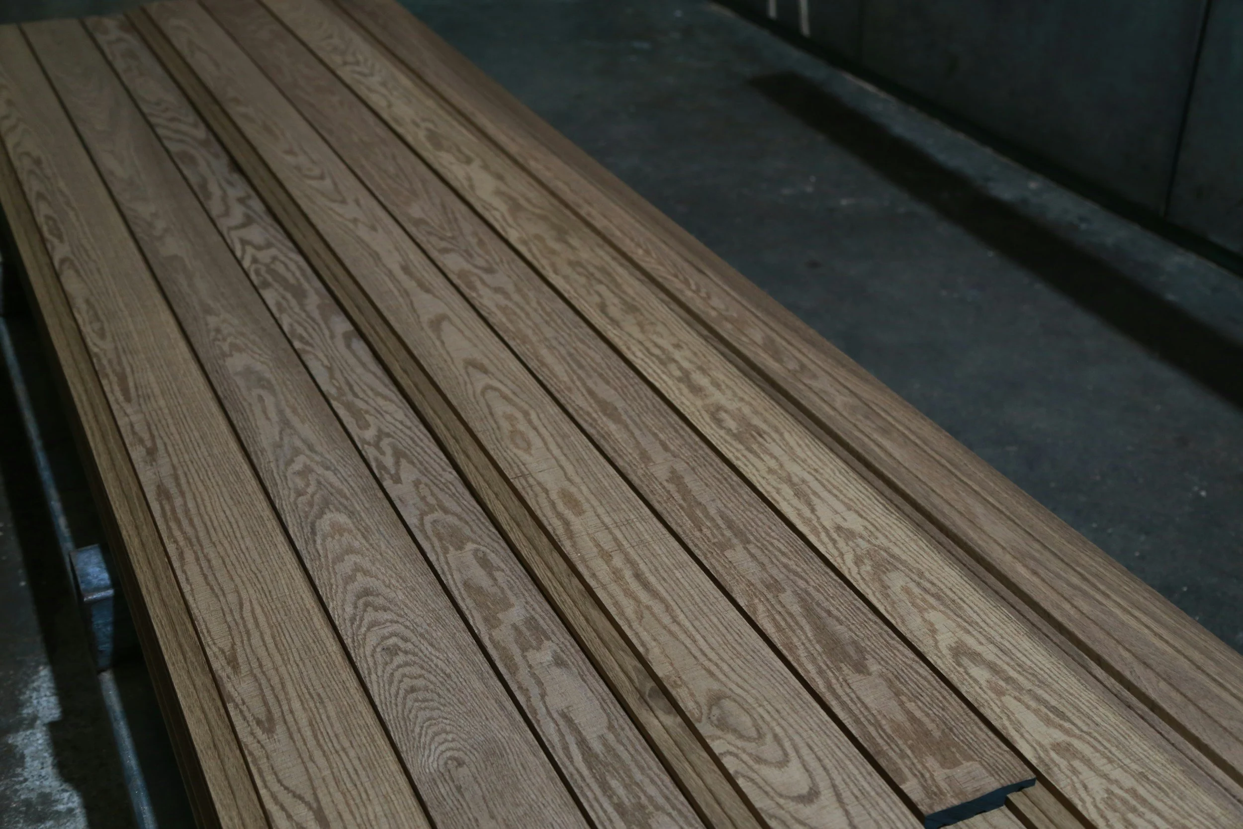 A wooden slatted bench or table placed on a concrete surface.