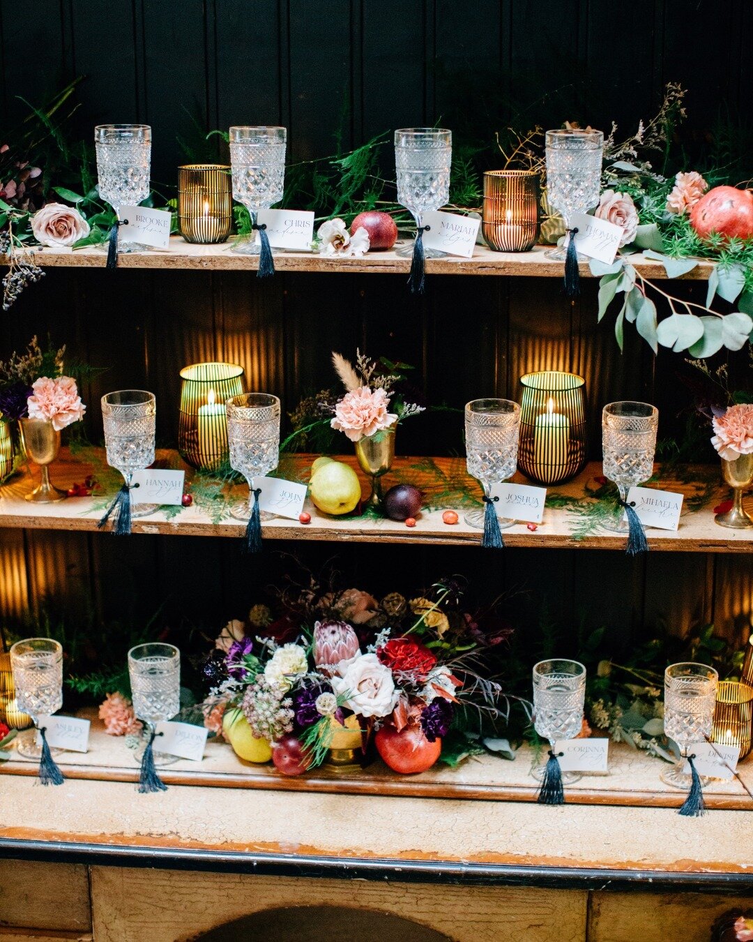 Letting your guests know where to sit doesn't have to be a sign with calligraphy! We love this moody, rich design scheme and the touches of florals and fruits in this escort display! 

Planner: @ivoryandsageevents
Floral: @posiesfloraldesign
Photogra