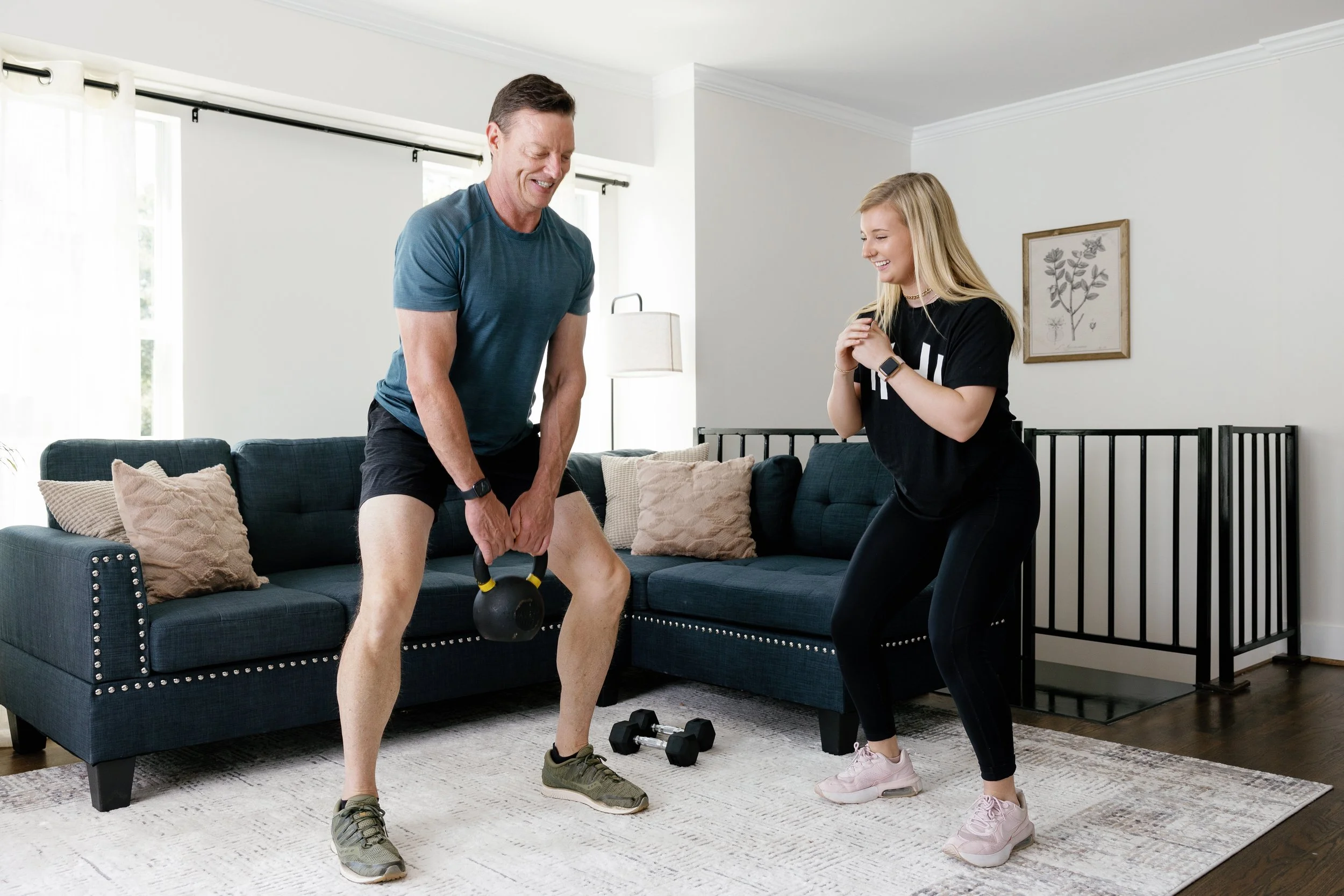 Personal trainer guiding a client through a kettlebell exercise during an in-home personal training session.