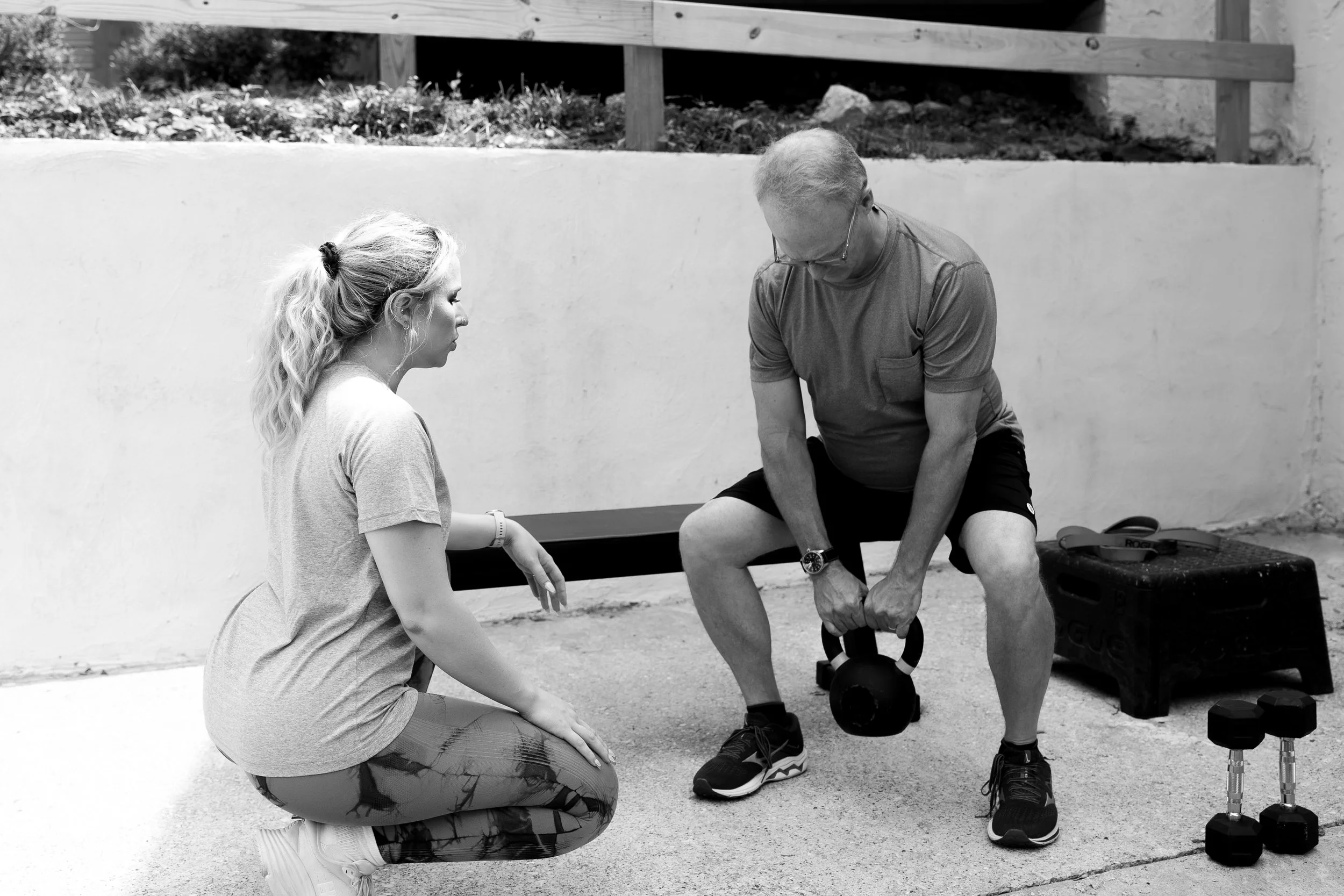 HOMEFIT personal trainer coaching an older adult through a kettlebell exercise to build functional strength and support healthy aging.