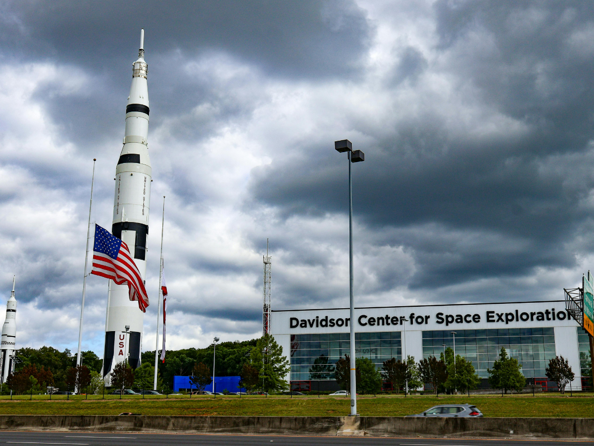 Rocket display outside the Davidson Center for Space Exploration in Huntsville, Alabama under dramatic storm clouds, showcasing aerospace history and Alabama tourism.