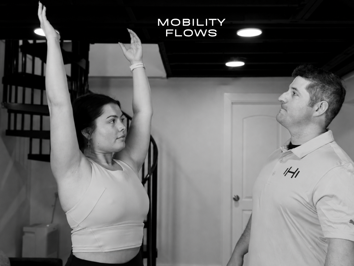 HOMEFIT personal trainer observes a client performing a gentle overhead reach with breathing during an in-home mobility flow.