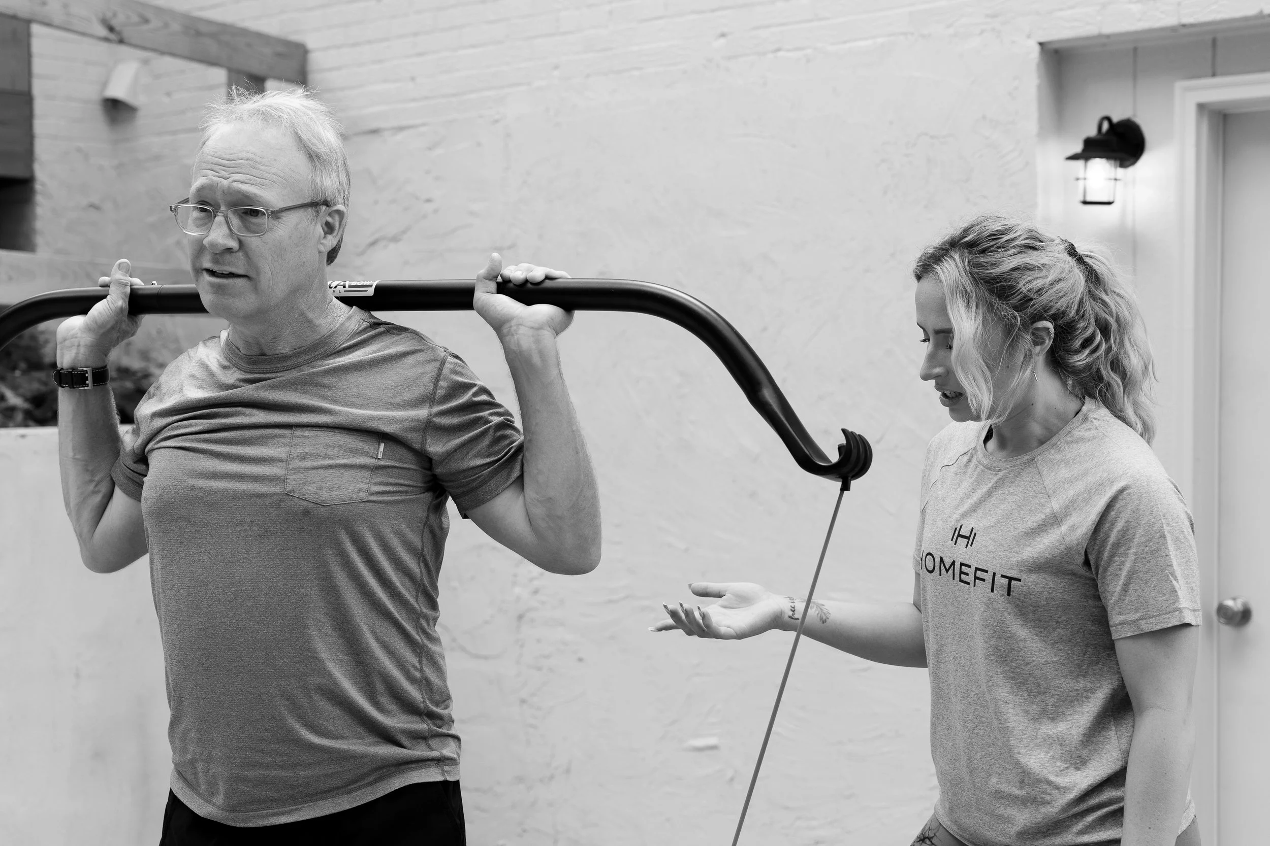 Older adult completing a resistance training exercise with guidance from a HOMEFIT personal trainer during an at-home fitness session.