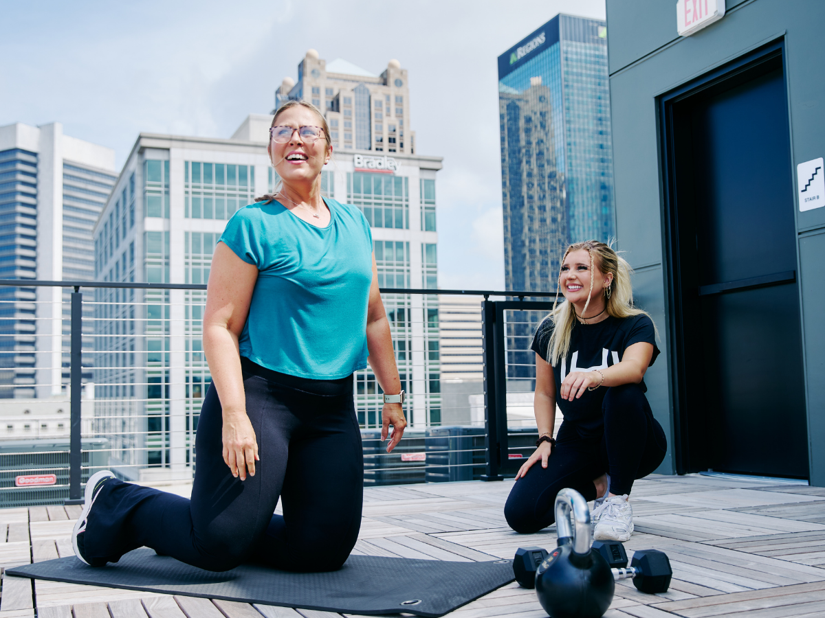 HOMEFIT personal trainer coaching a client during a rooftop workout in downtown Birmingham, Alabama with kettlebells and city skyline views, promoting mobile personal training and functional fitness.