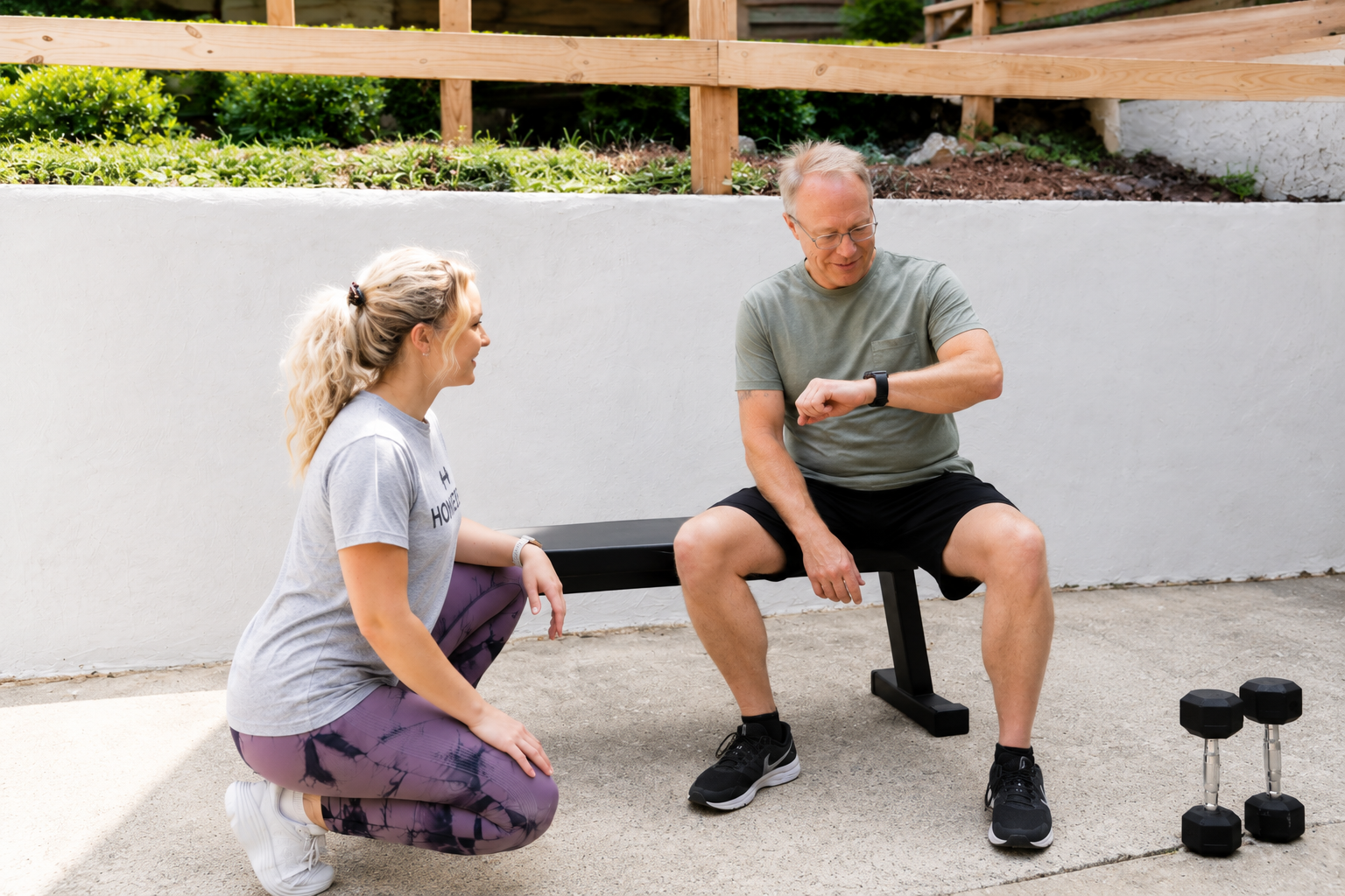 HOMEFIT in-home personal training client checking his fitness watch during an outdoor workout with a personal trainer.