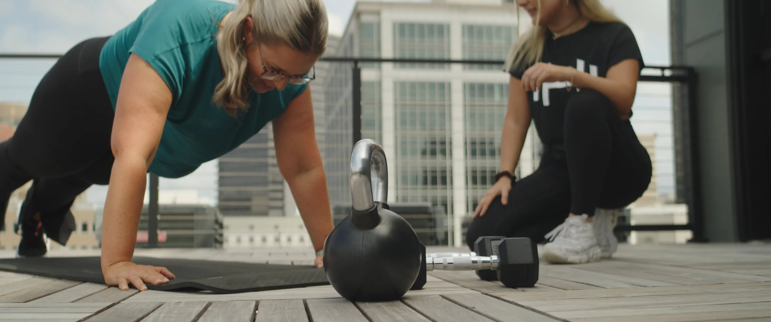 HOMEFIT personal trainer leading an outdoor strength training workout with kettlebells and dumbbells to improve fitness, mobility, and overall health.