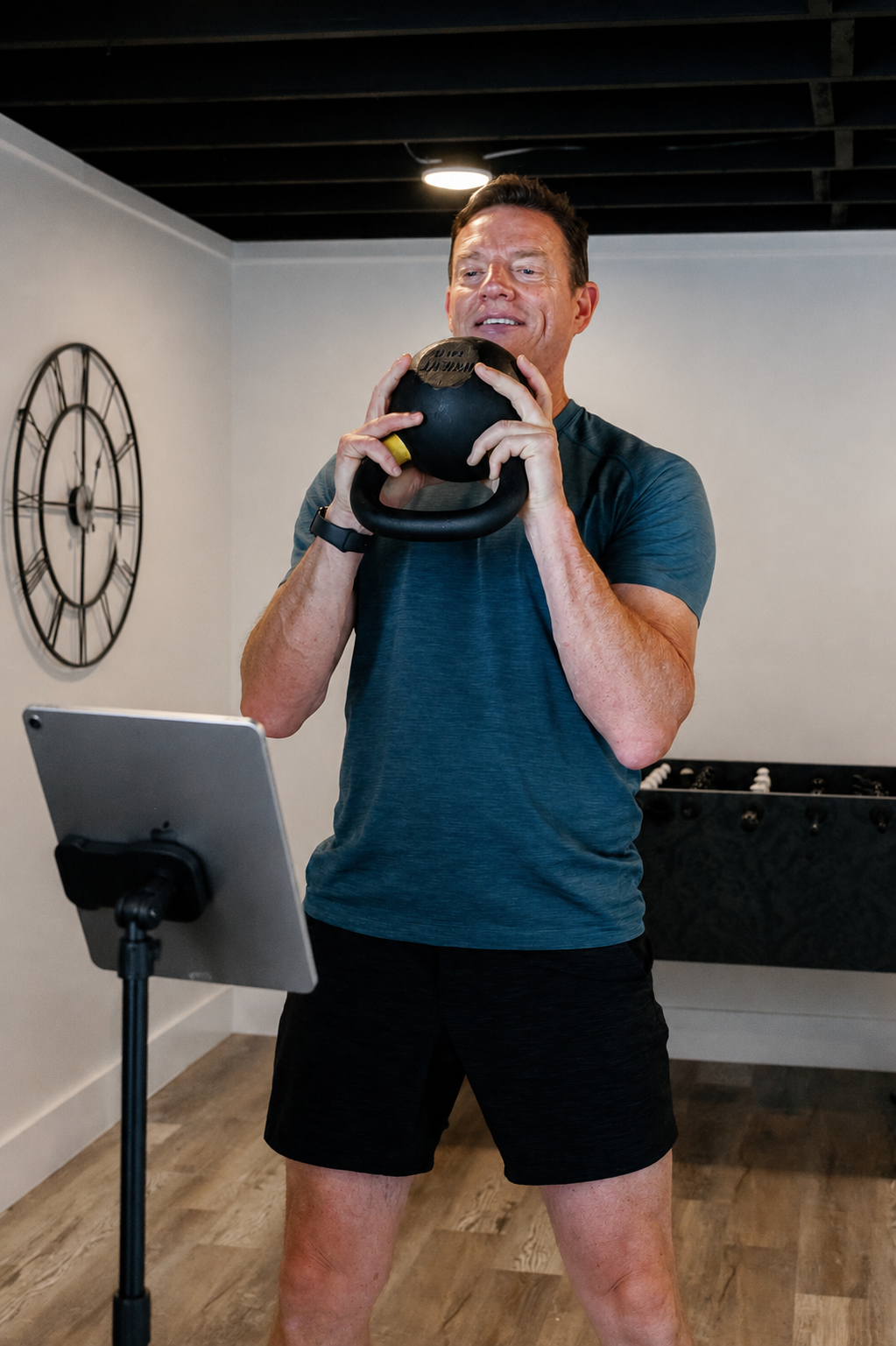 HOMEFIT trainer participating in a virtual fitness session on a tablet, highlighting real-time online personal training and remote workout accountability.