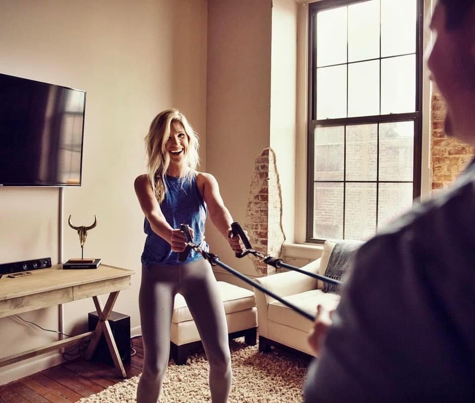HOMEFIT female personal trainer guiding a client through a dumbbell strength training exercise, demonstrating proper form, individualized fitness coaching, and progressive resistance training.