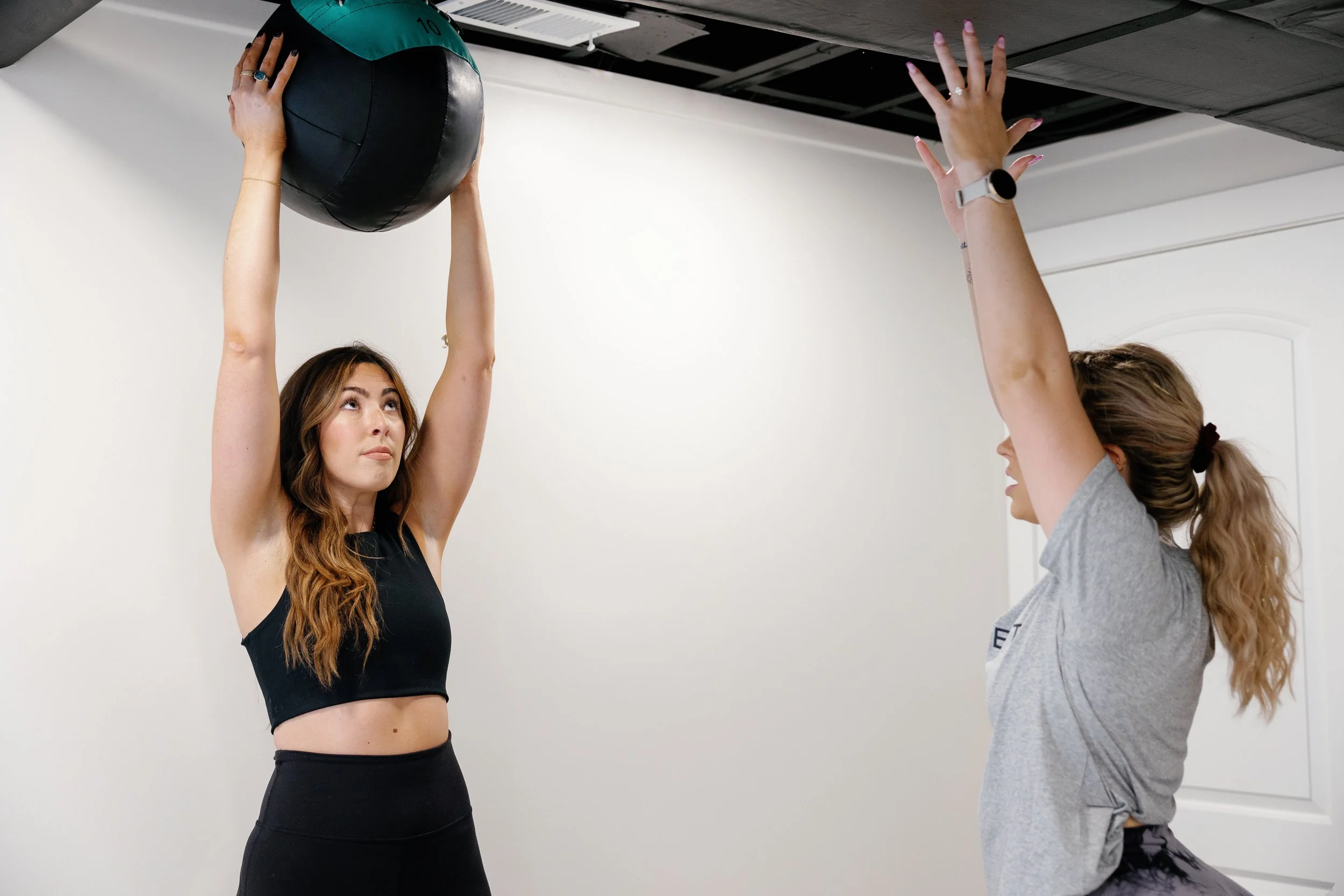 HOMEFIT personal trainer coaching a client through a medicine ball exercise during an in-home strength training workout.
