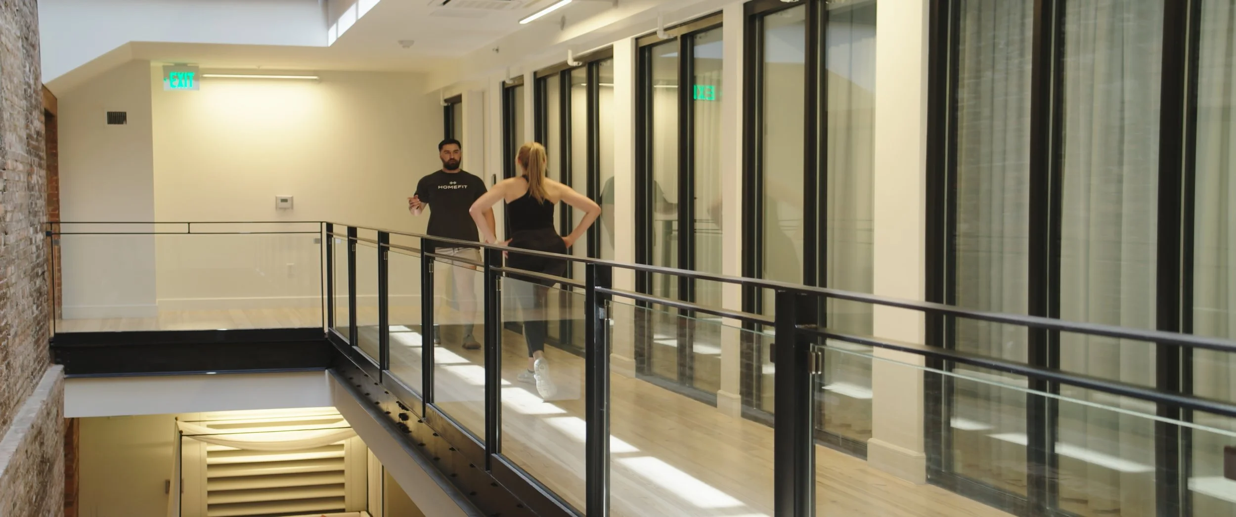 HOMEFIT personal trainer leading a client through an indoor walking workout in a modern hotel building for convenient vacation fitness.