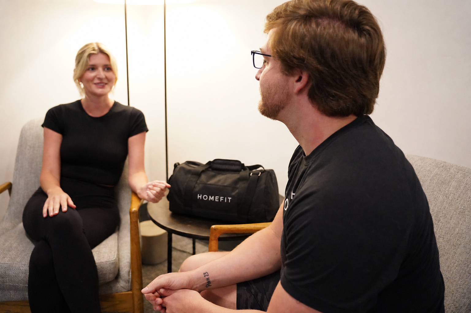 HOMEFIT trainer meeting with a client at home with a branded equipment bag ready for an in-home personal training session.