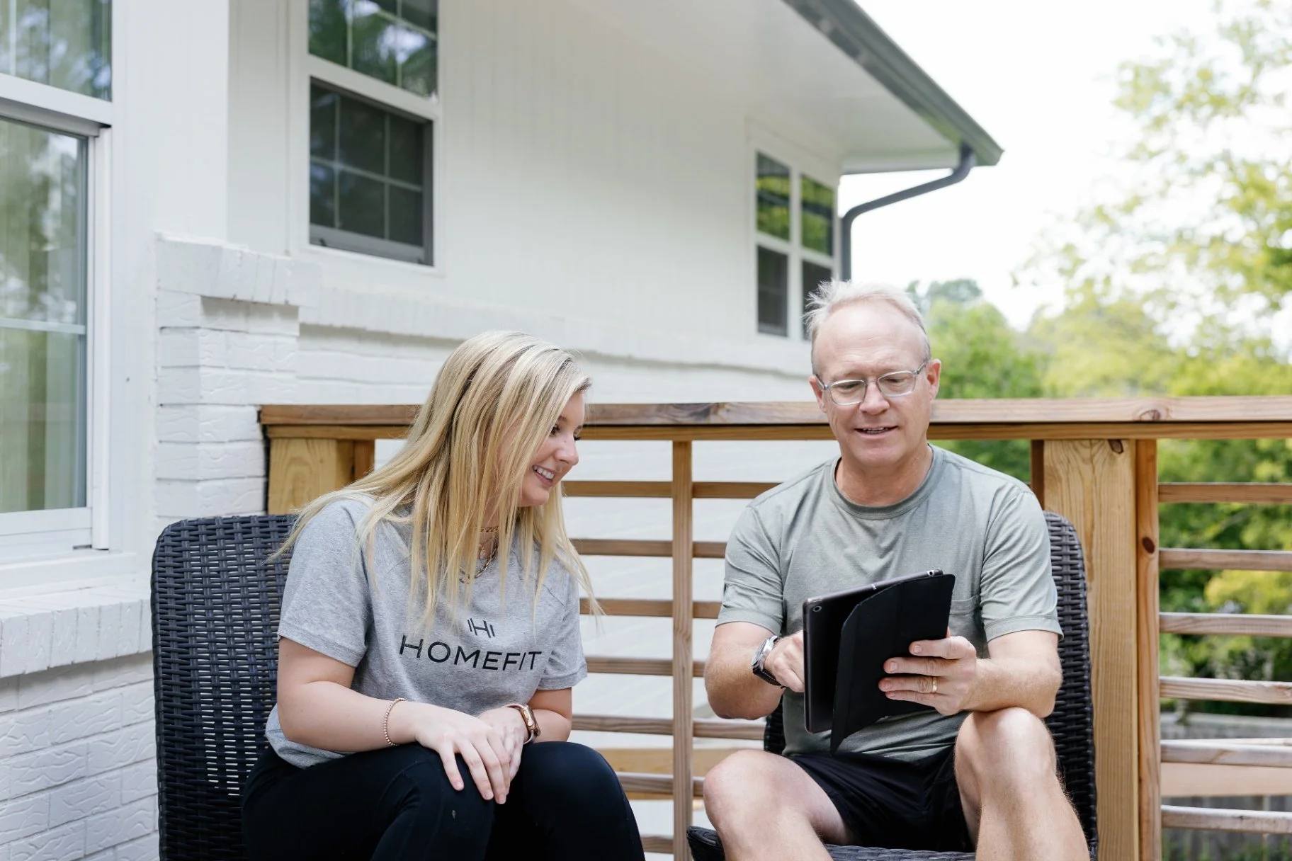 Home fitness coaching session with trainer and client reviewing exercise program on tablet, highlighting convenient personalized workouts at home