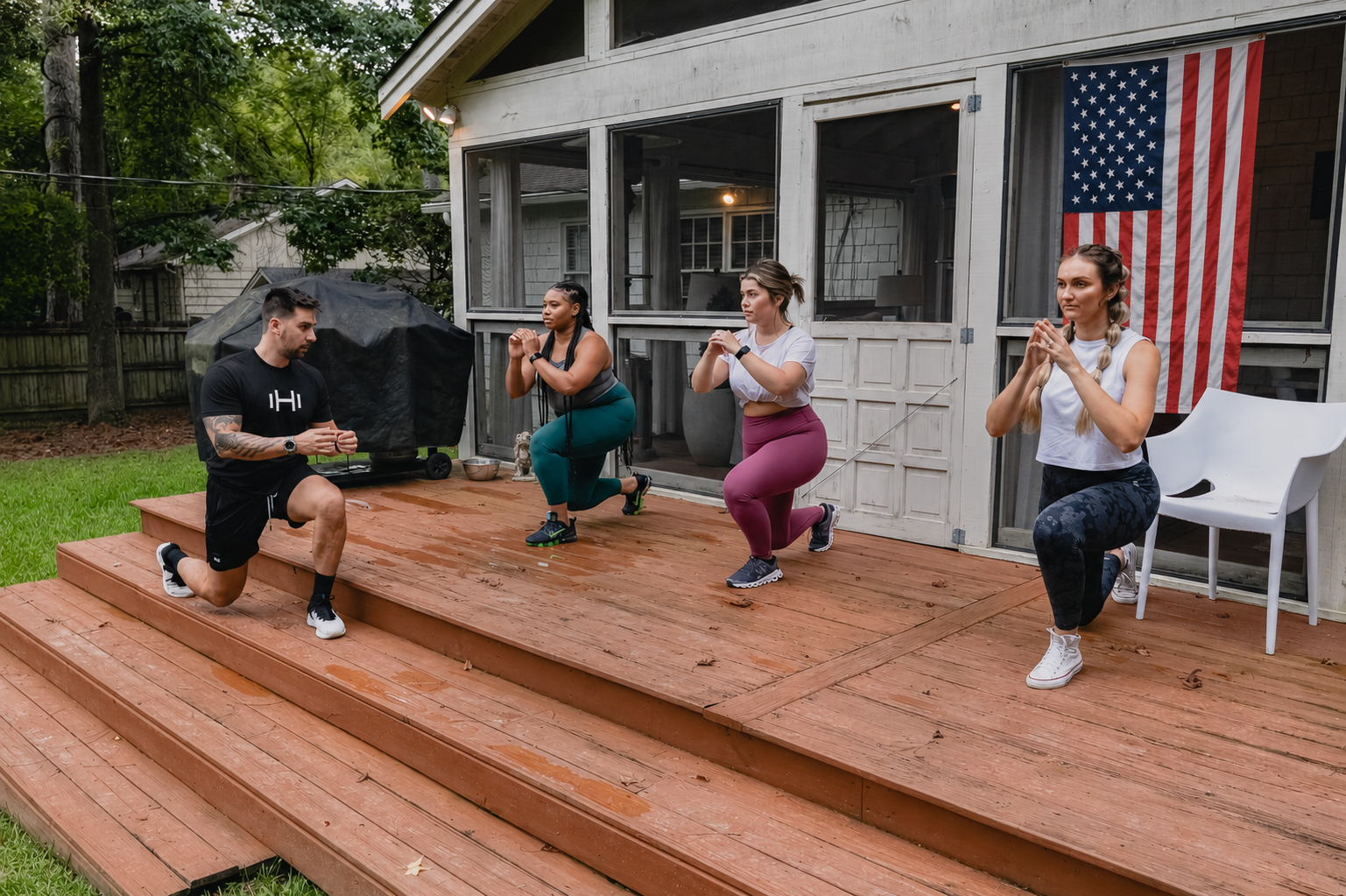HOMEFIT personal trainer leading three women through supported lunges during an outdoor group workout on a backyard deck.