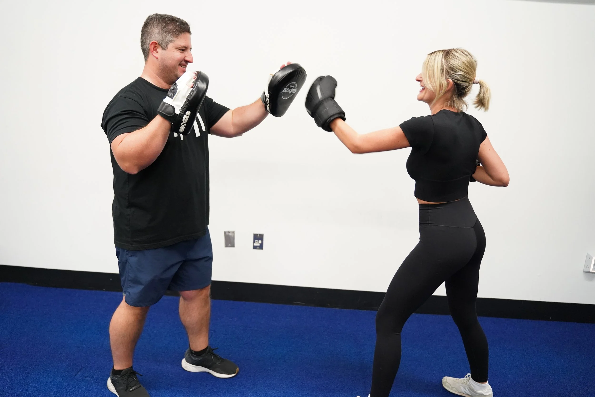 HOMEFIT trainer guides a client through an overhead medicine ball exercise during an in-home workout.