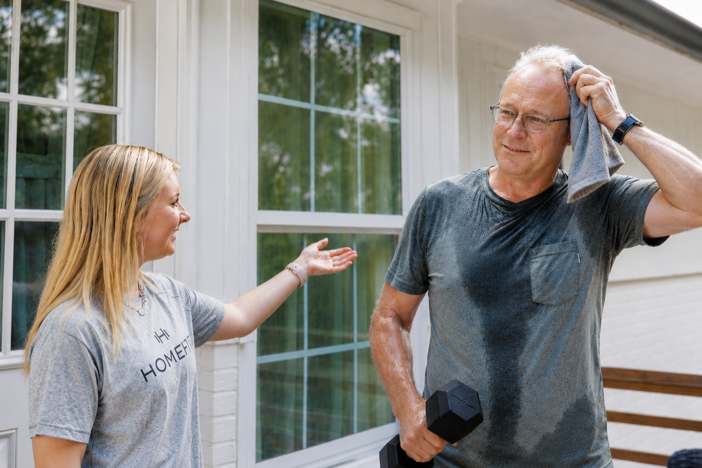 HOMEFIT trainer encouraging an older adult client after an outdoor workout as he wipes sweat from his forehead, showcasing fitness progress and healthy aging.