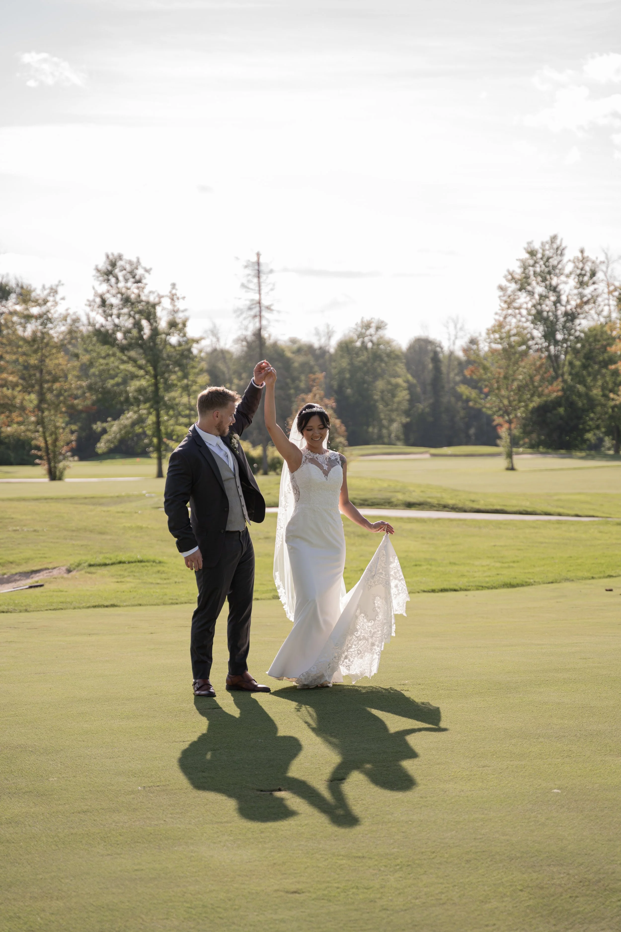 A bride and groom dancing on a golf course during daytime.
