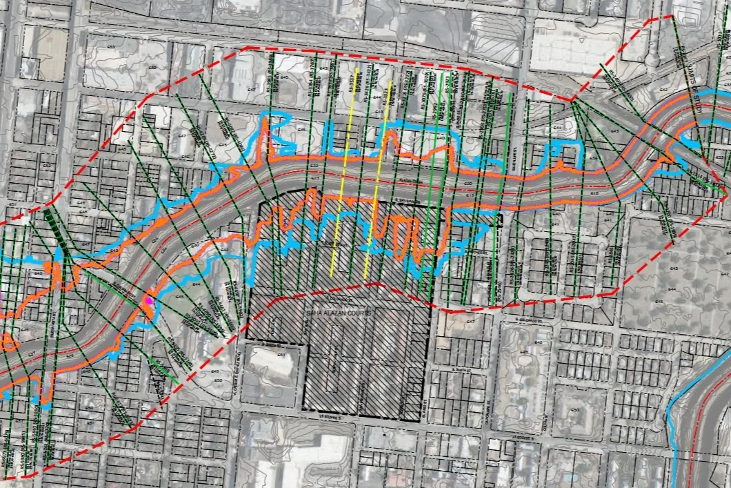 A detailed city planning map showing terrain contours, water features in blue, roads in gray and orange, property plots, and green drainage or utility lines. The map includes annotations and measurements, with a large shaded area labeled 'Saha Alazan Courts'.