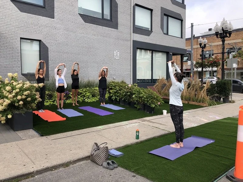 people doing yoga in pop-up park on the road