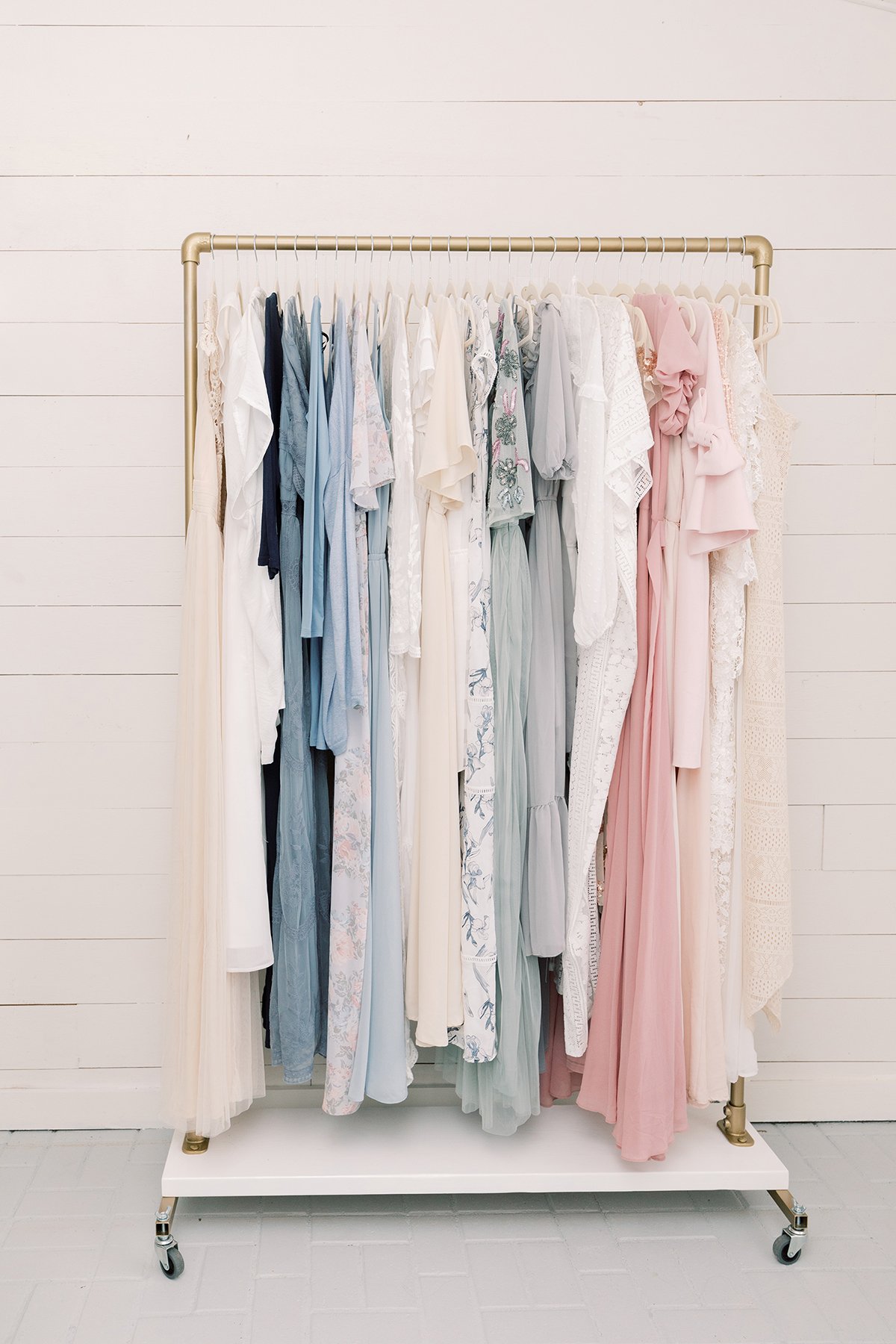A standing rack with pastel color womens dresses hanging on the rack.