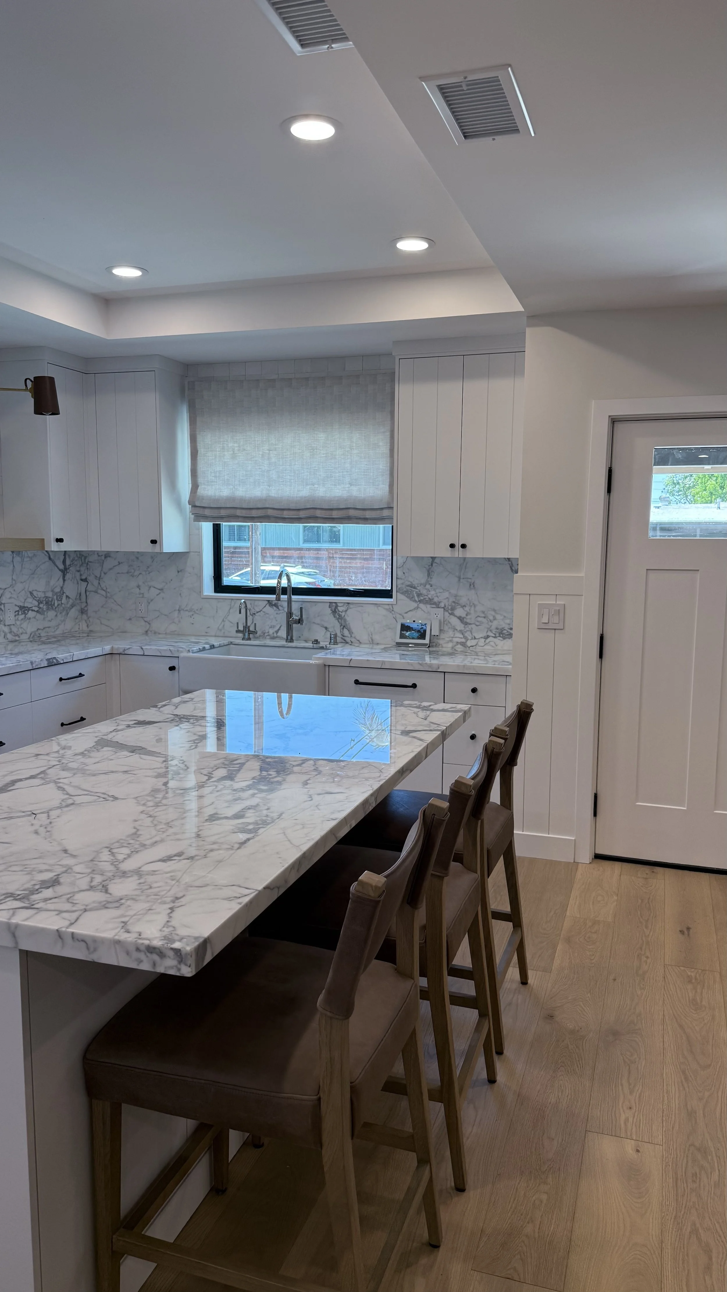 Natural stone waterfall kitchen island with counter seating and white custom cabinetry in the Iroquois whole-home remodel.