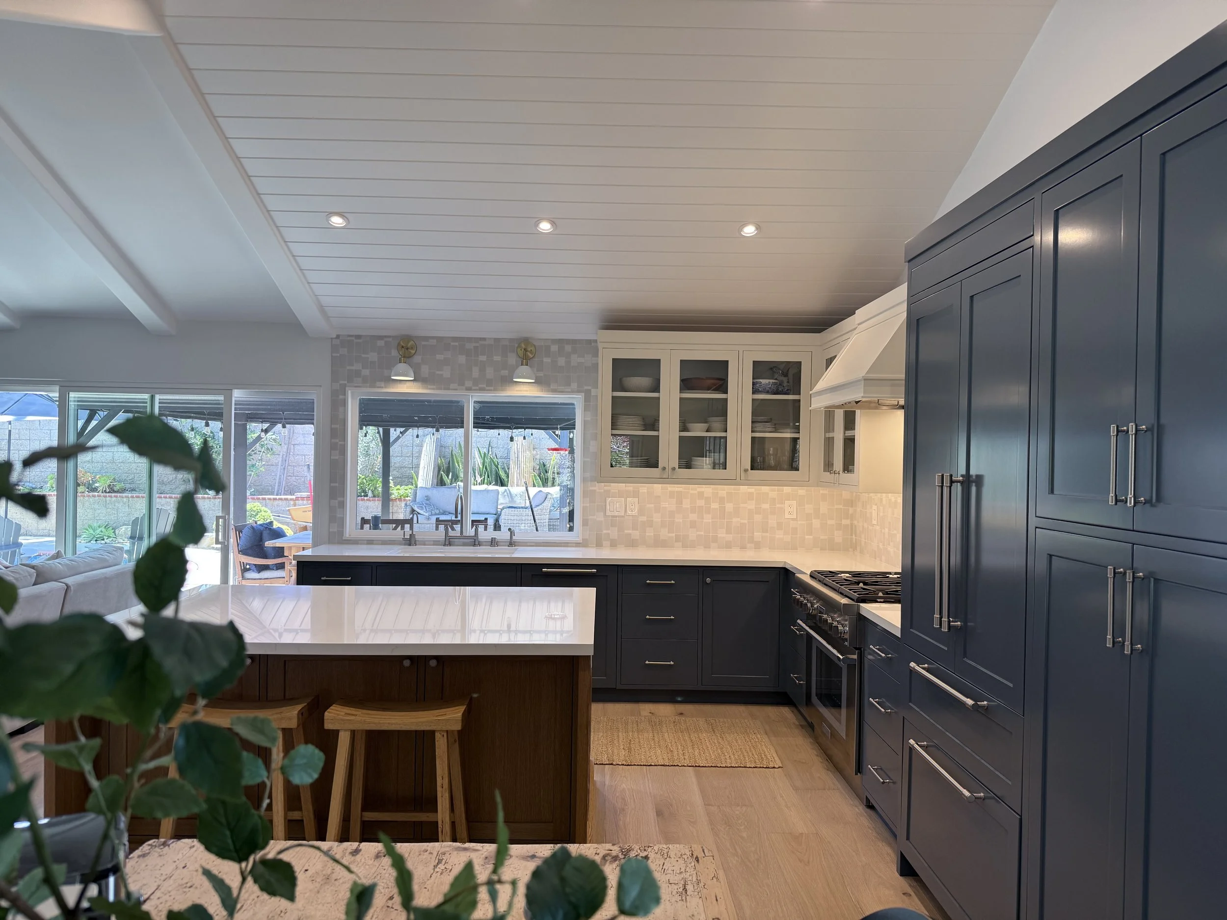 Open-concept kitchen featuring custom blue cabinetry, white countertops, large island, and handmade tile backsplash.