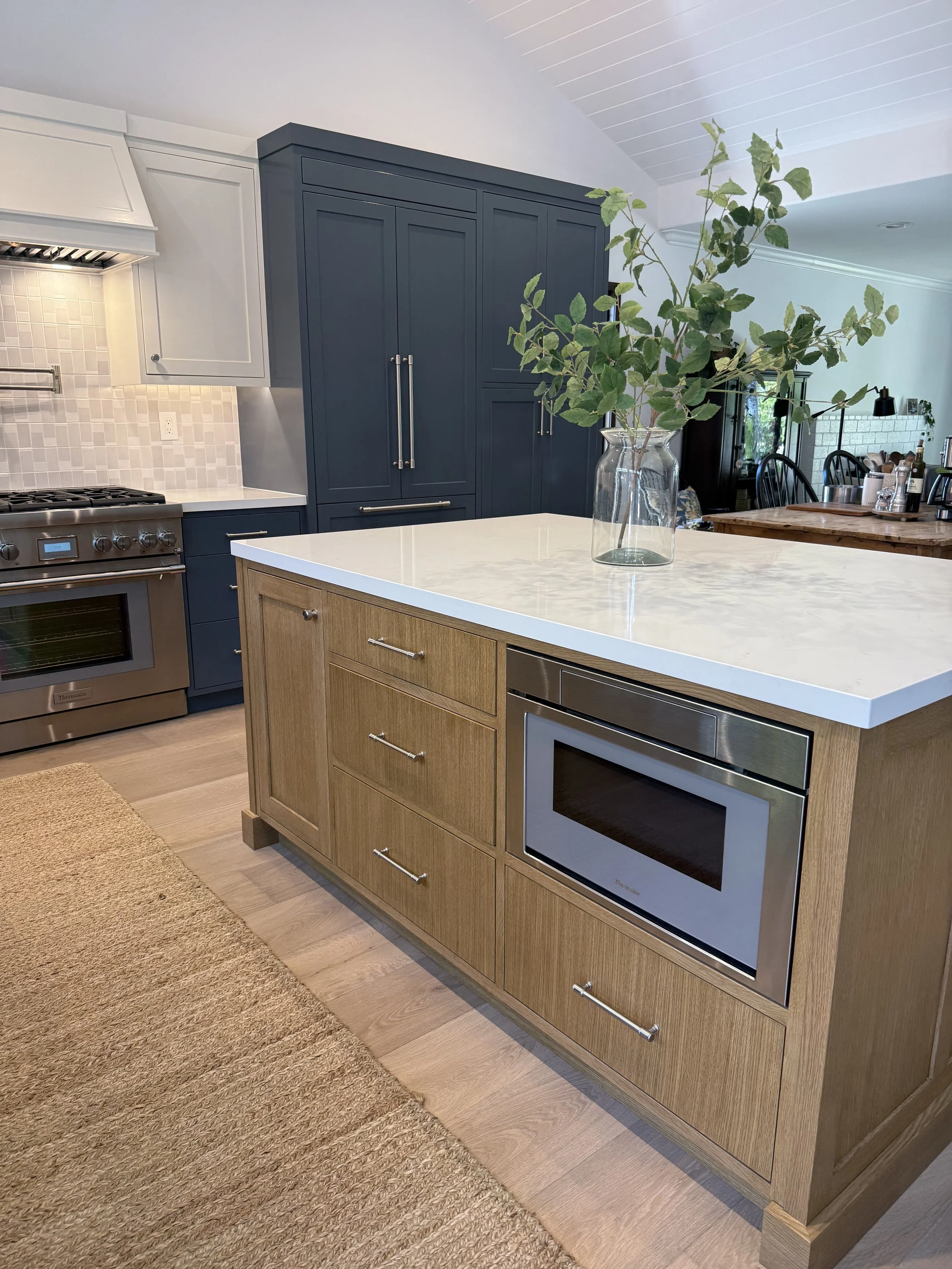 Waterfall-edge kitchen island with textured wood finish, quartz countertop, and custom blue cabinetry.