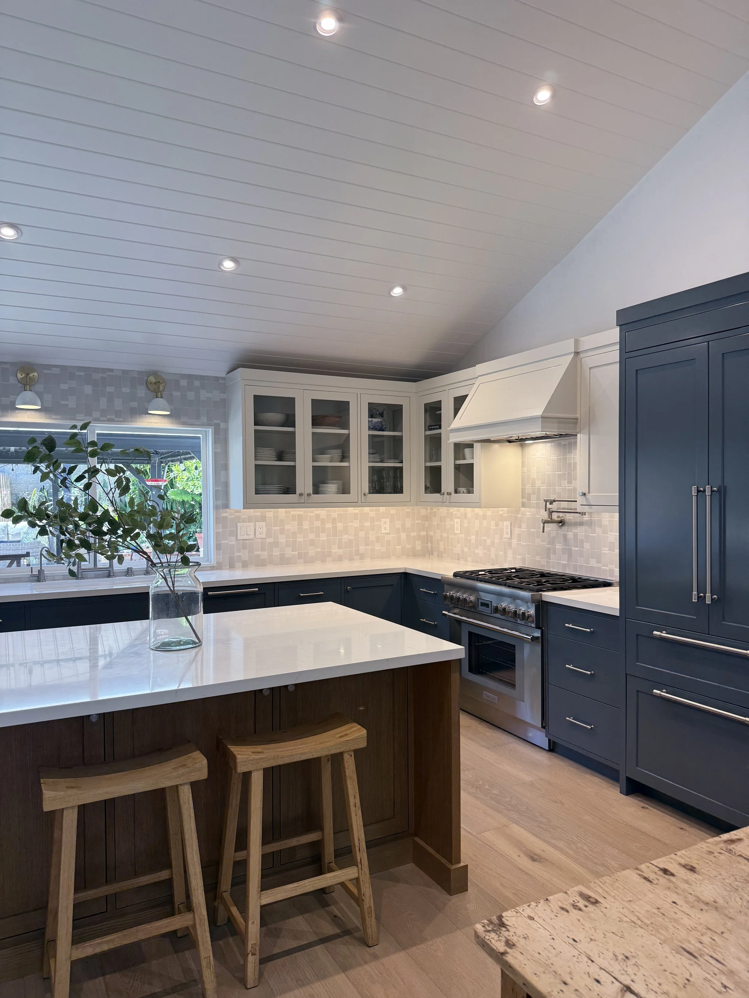 Kitchen remodel with large waterfall island, custom cabinetry, brass fixtures, and natural light.