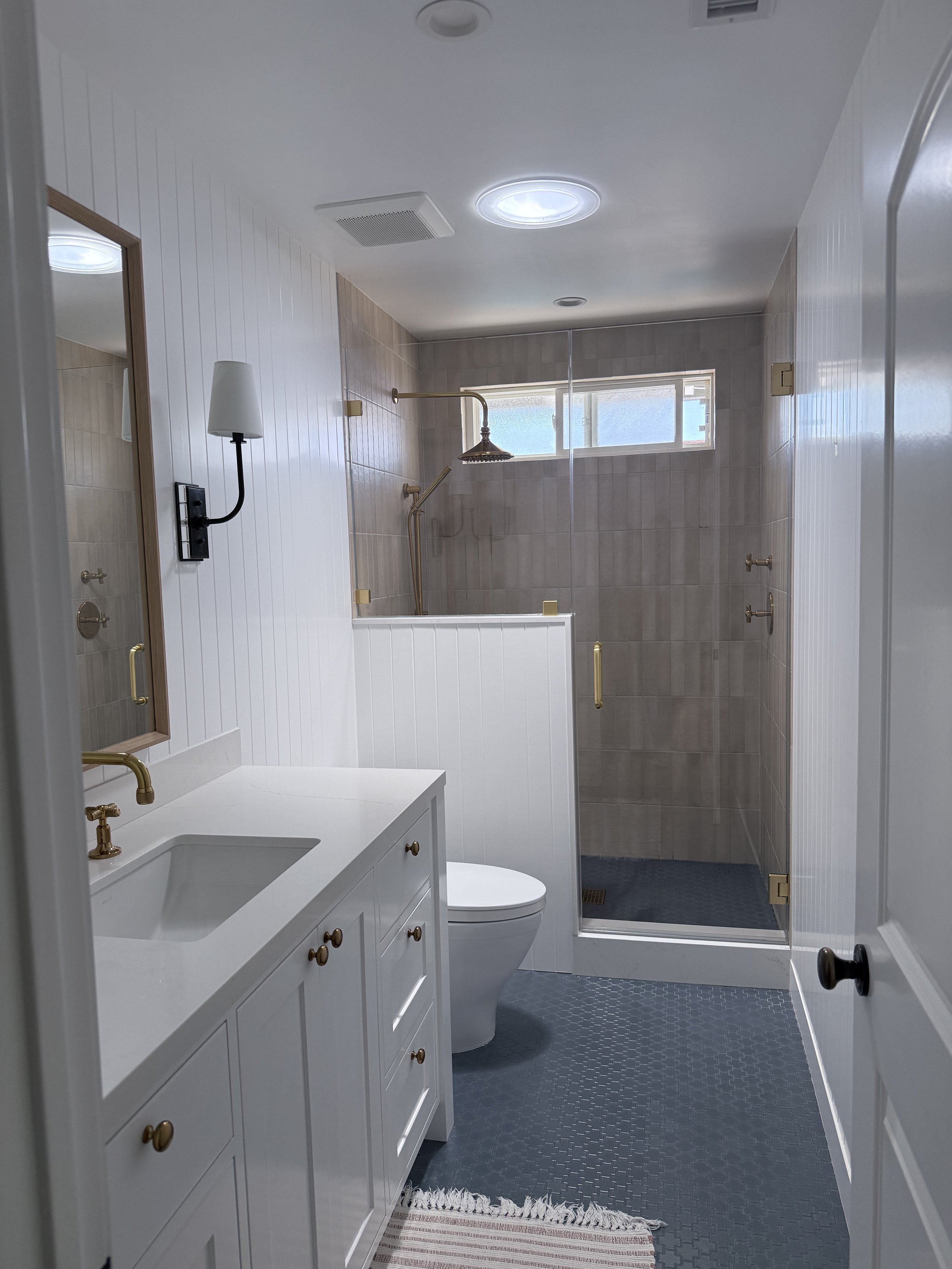 Guest bathroom remodel with grey-blue Swiss cross floor tile, custom vanity, and walk-in shower.