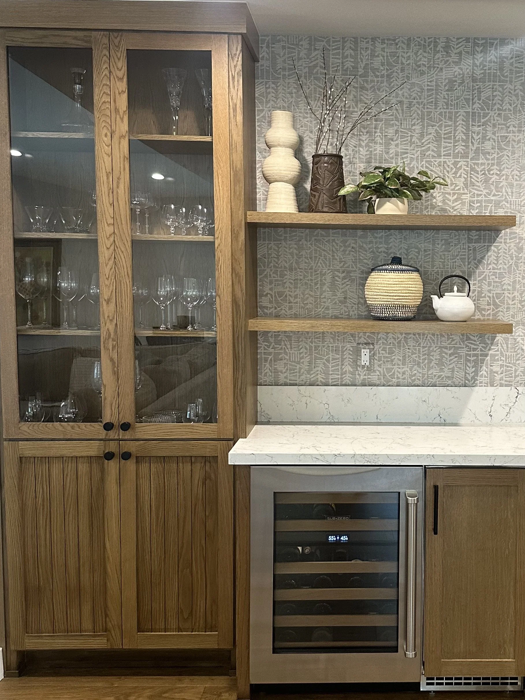 Custom dry bar with wood cabinetry and patterned tile backsplash.