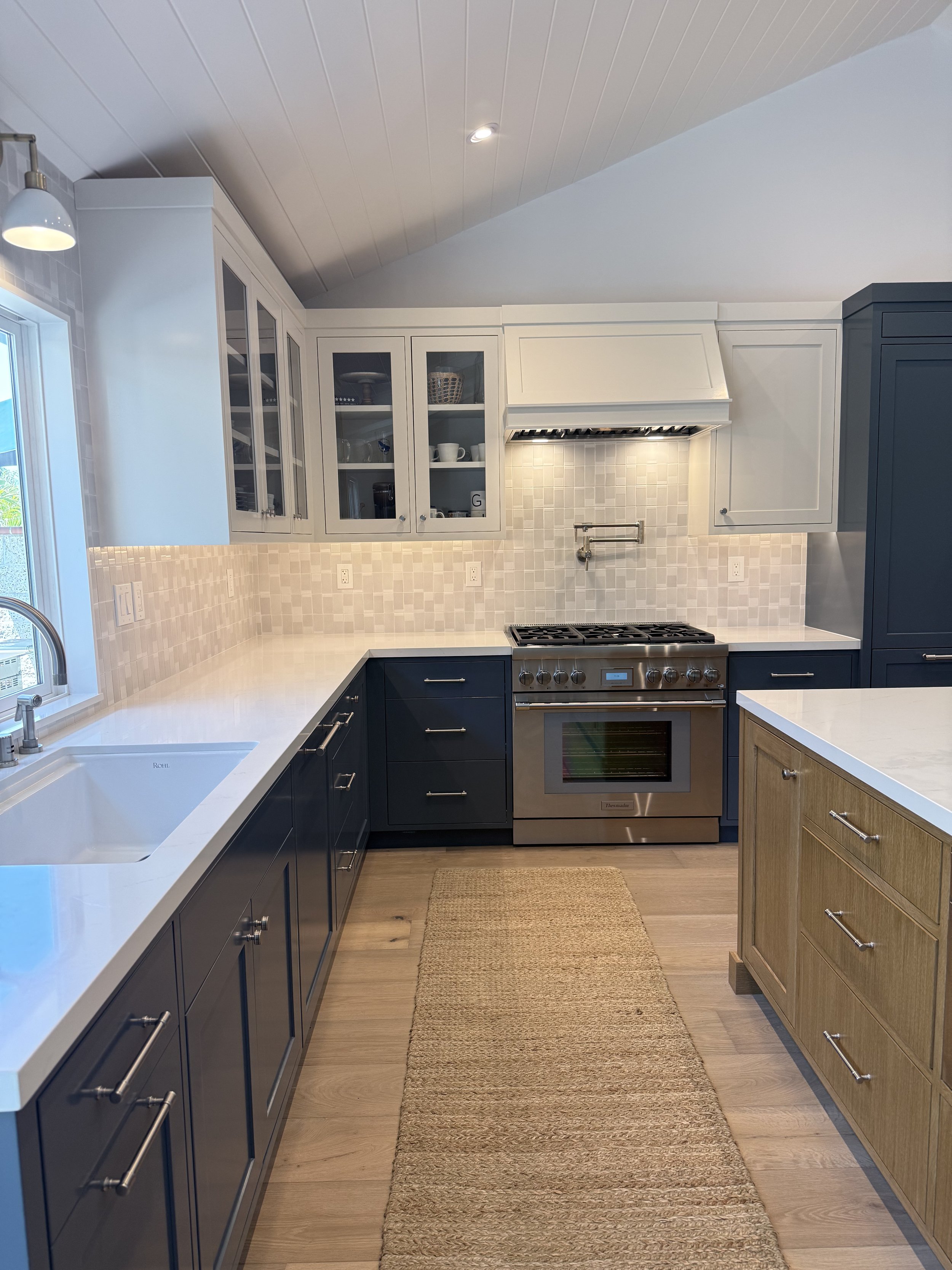 Custom kitchen featuring a Wolf range, handmade ceramic backsplash, blue inset cabinets, and pot filler.