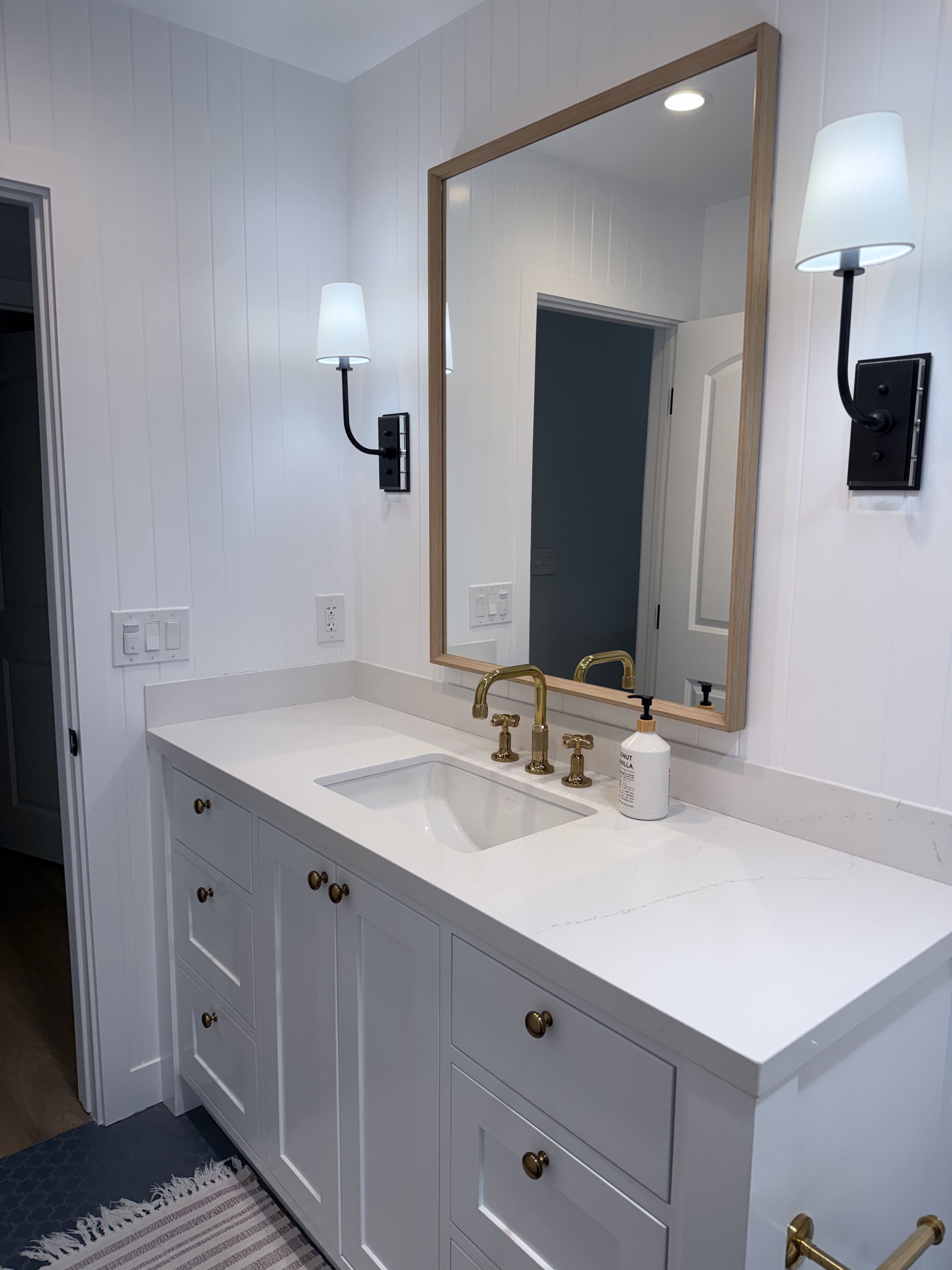 Primary bathroom remodel with custom vanity, white countertop, walk-in shower, and porcelain tile flooring.