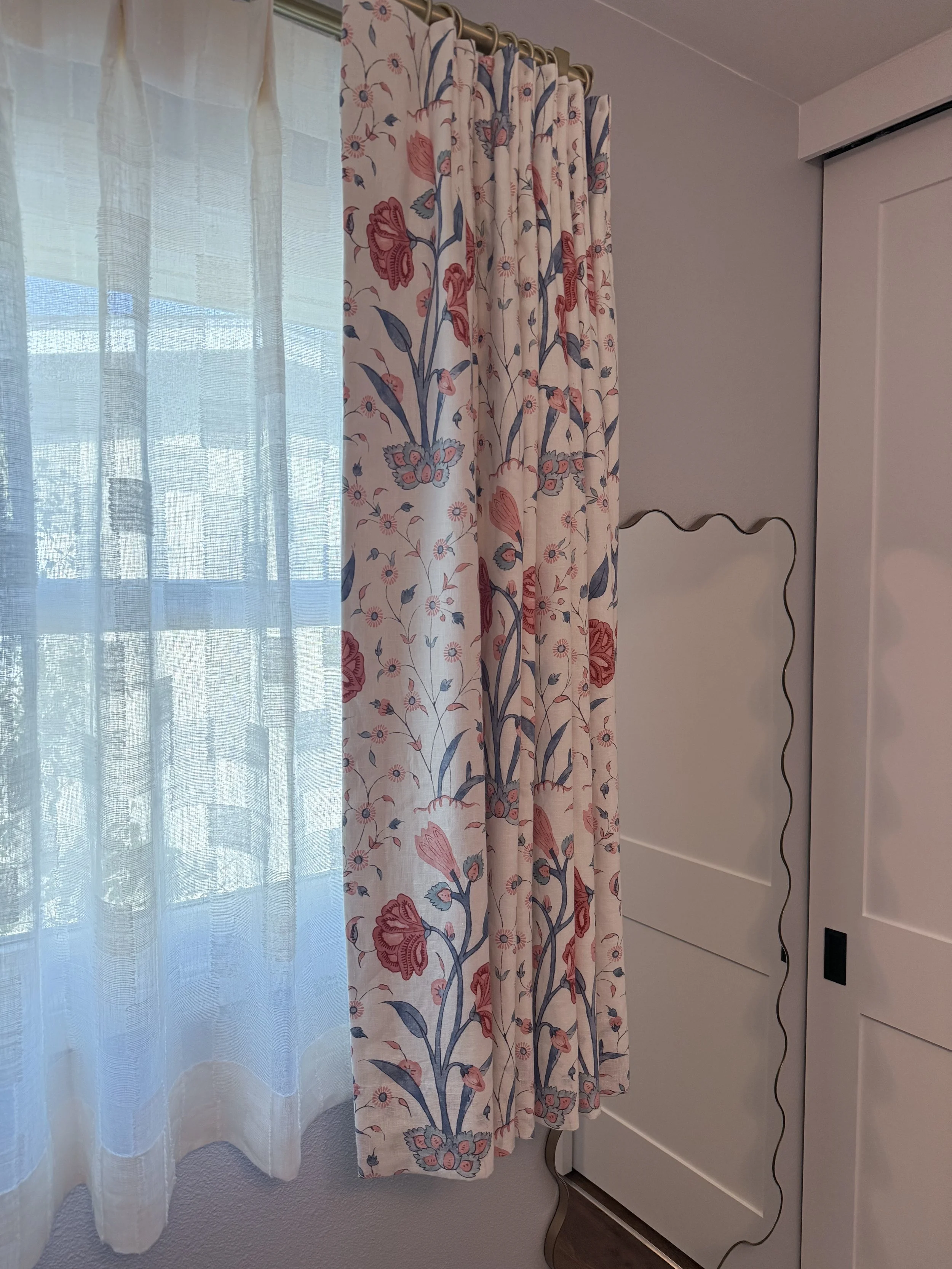 Floral custom drapery with woven shades in children's bedroom.