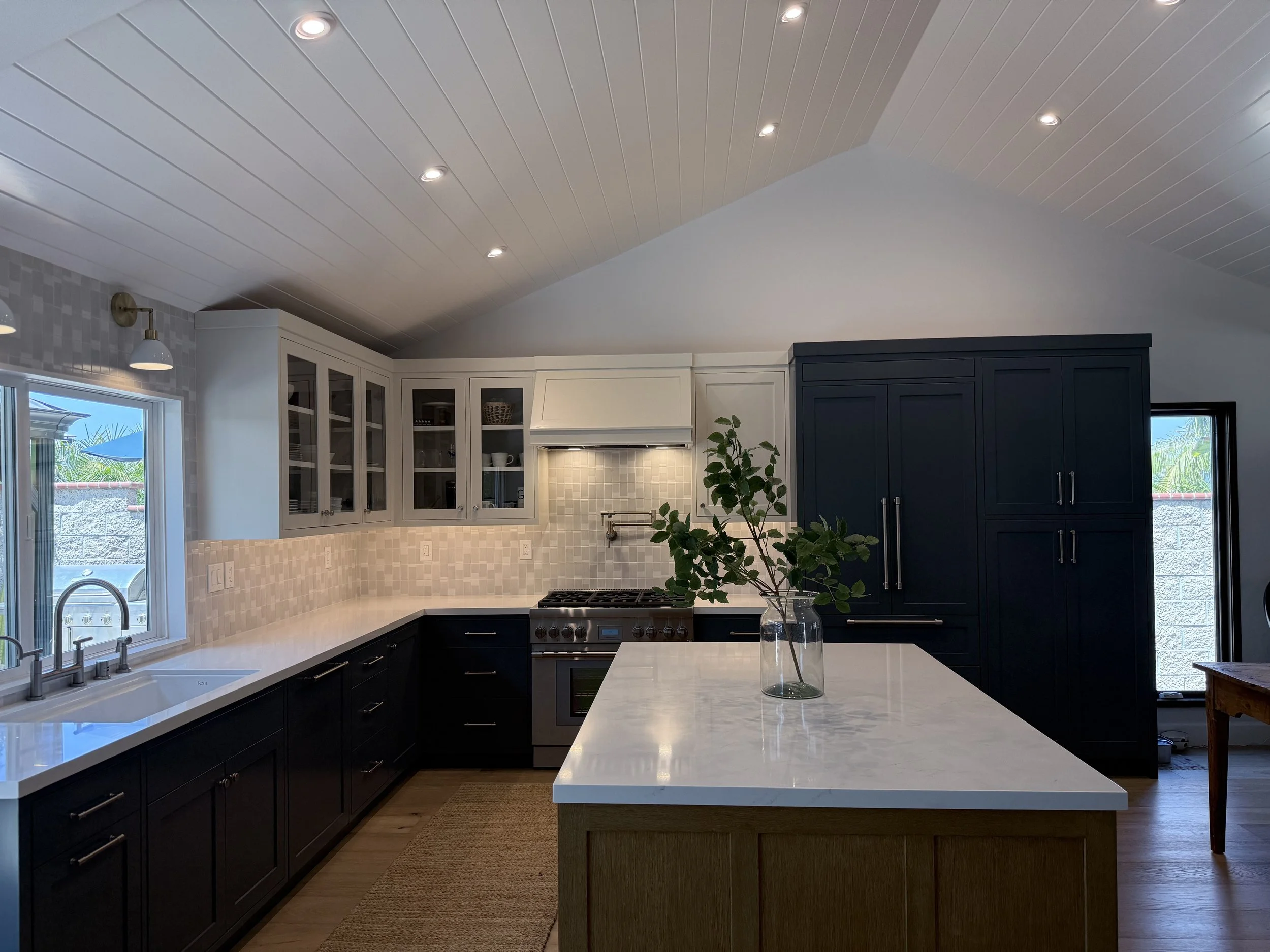 Custom kitchen with blue inset cabinets, white quartz countertops, Saltillo tile flooring, and spacious island.