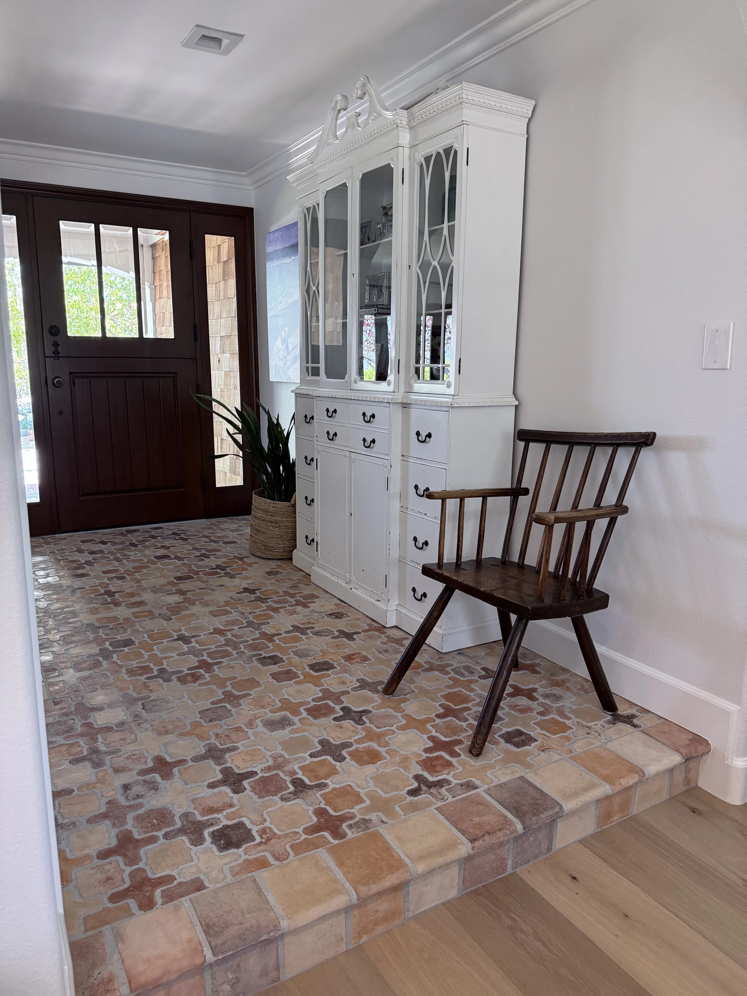 Entryway with colorful Saltillo tile flooring, white walls, and warm wood front door in a Laguna Niguel home remodel.