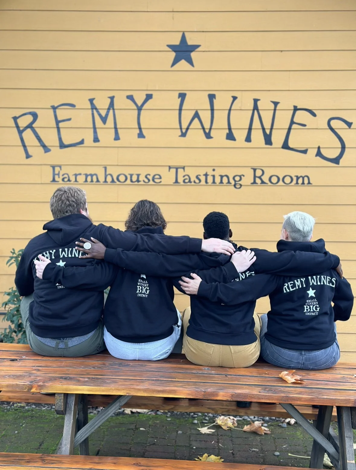 4 people sitting on a bench with their backs facing the camera