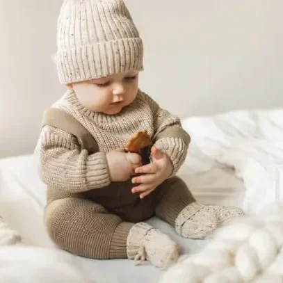 a-5-month-old-baby-boy-in-cotton-knitwear-laying-on-a-bed.webp