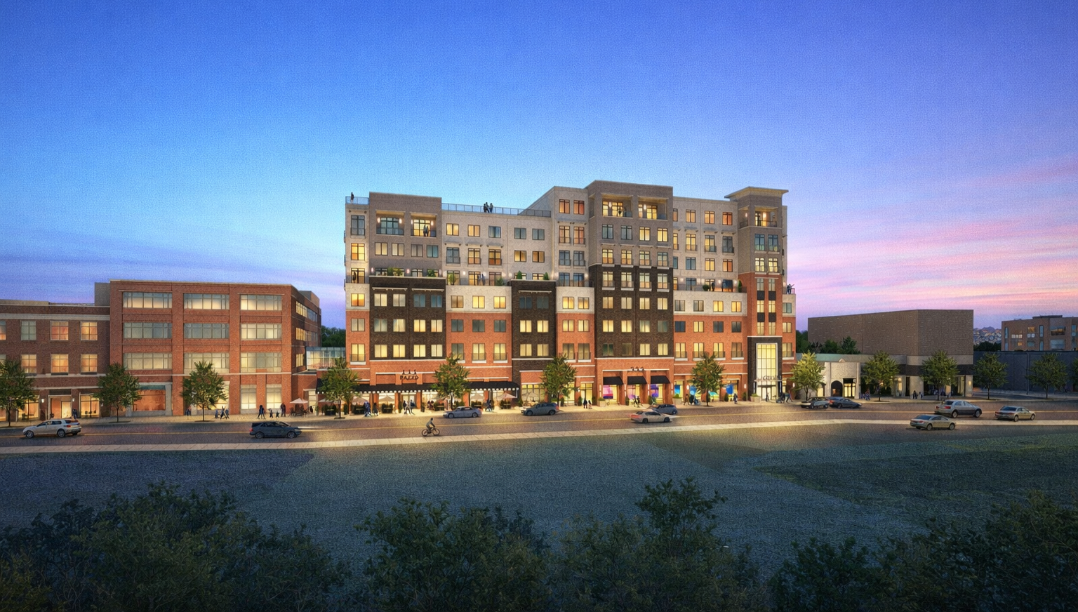 Rendering of a multi-story mixed-use building with residential units above, retail shops on the ground floor, and trees along the sidewalk at dusk.