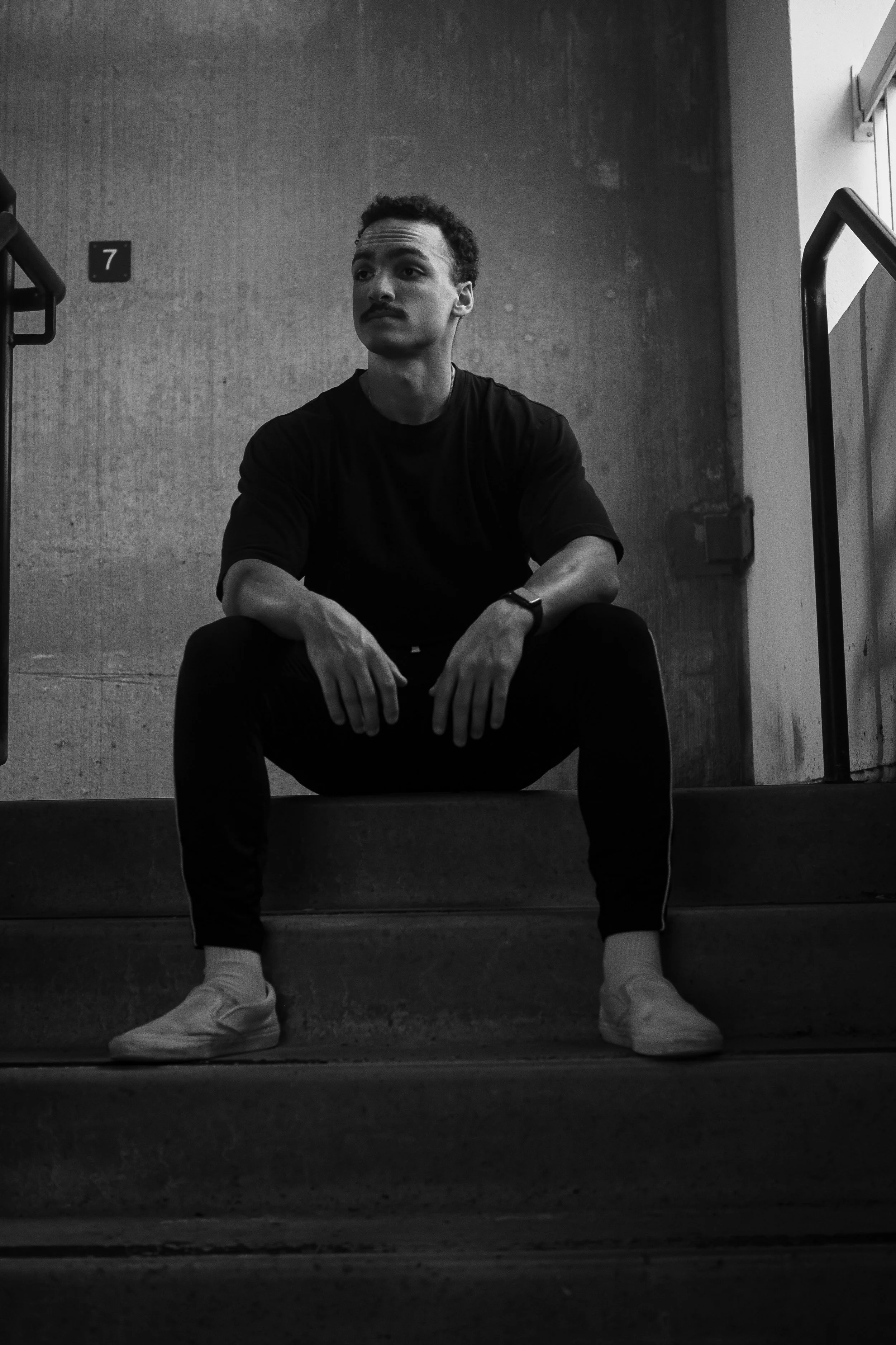 black and white photo of man sitting in stairwell photoshoot