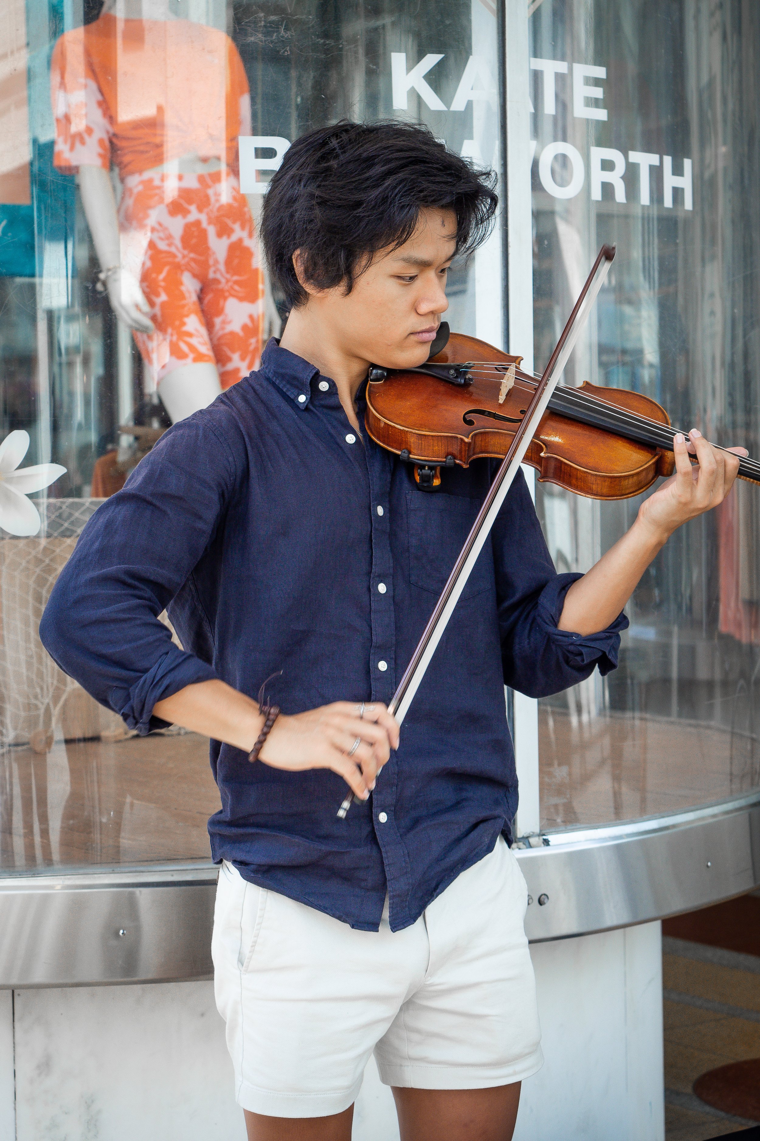 man playing violin in front of shopping store