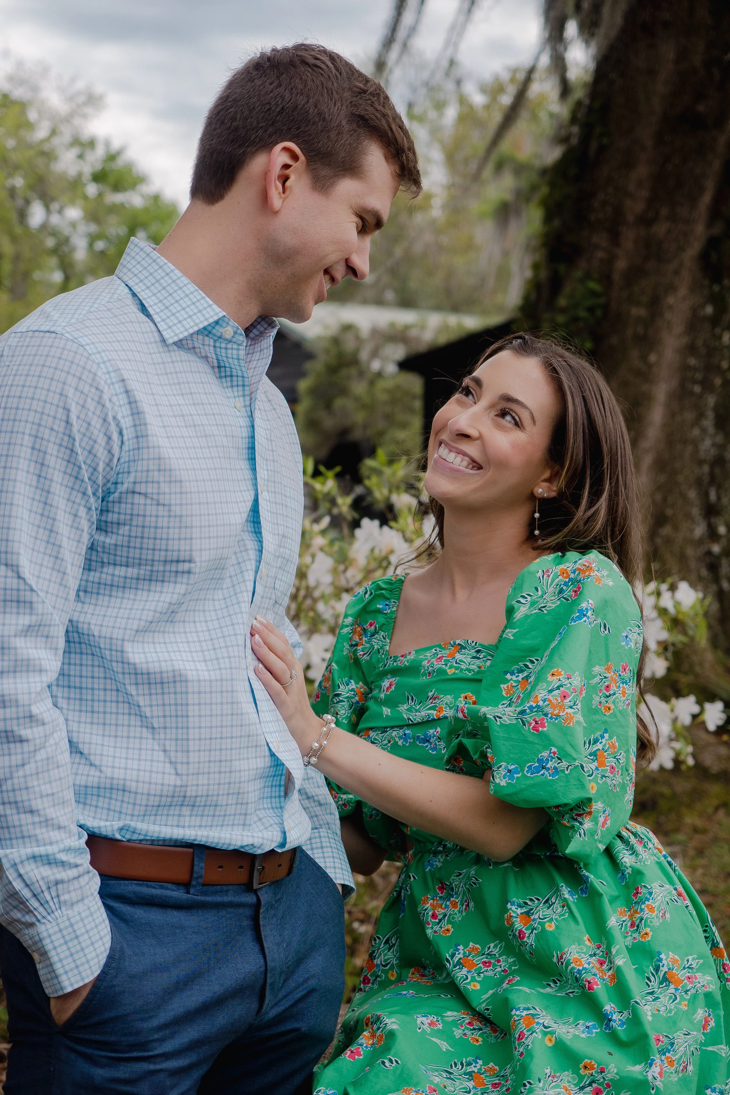 couple smiling at each other in park engagement photoshoot
