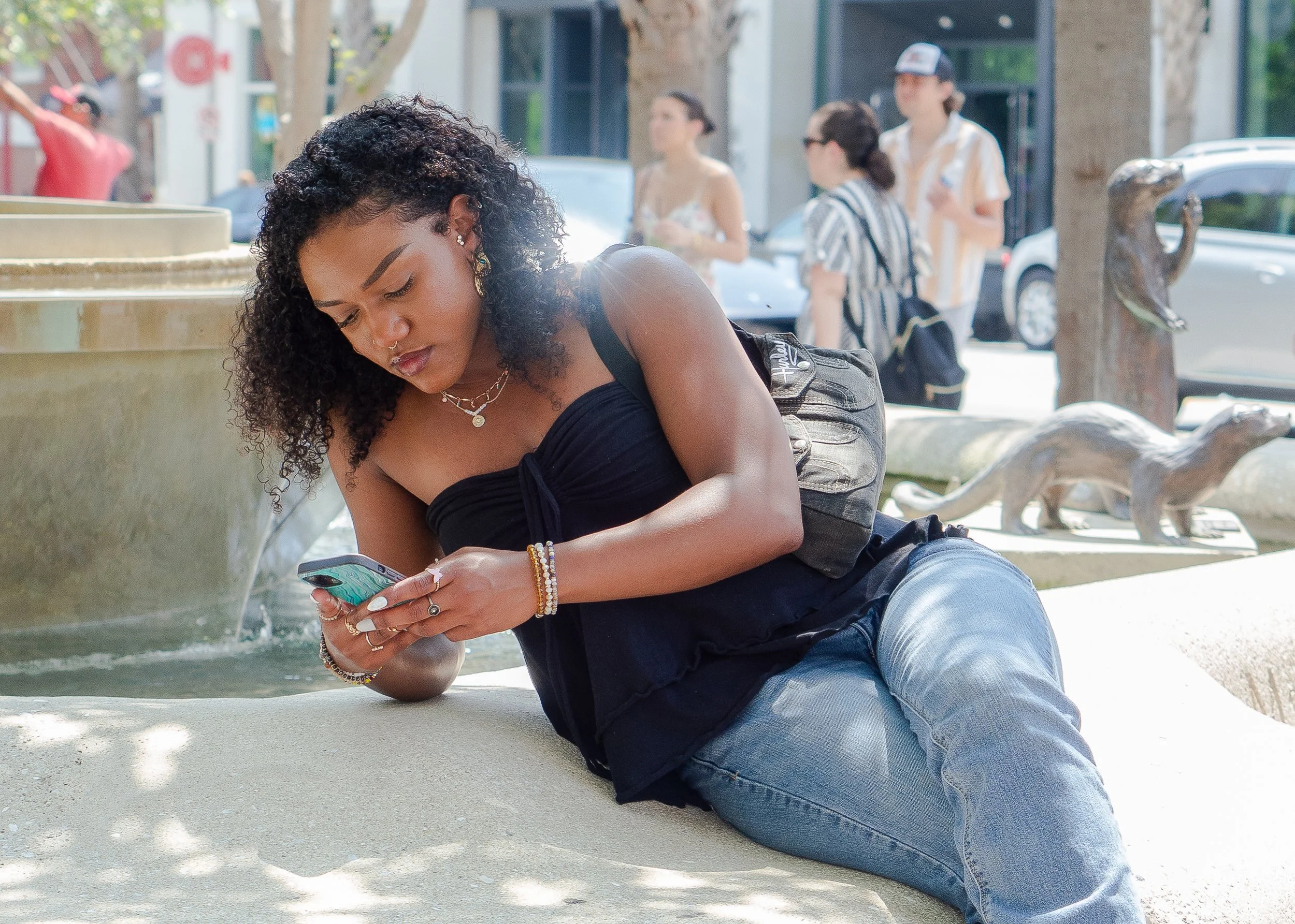 women on phone sitting on fountain