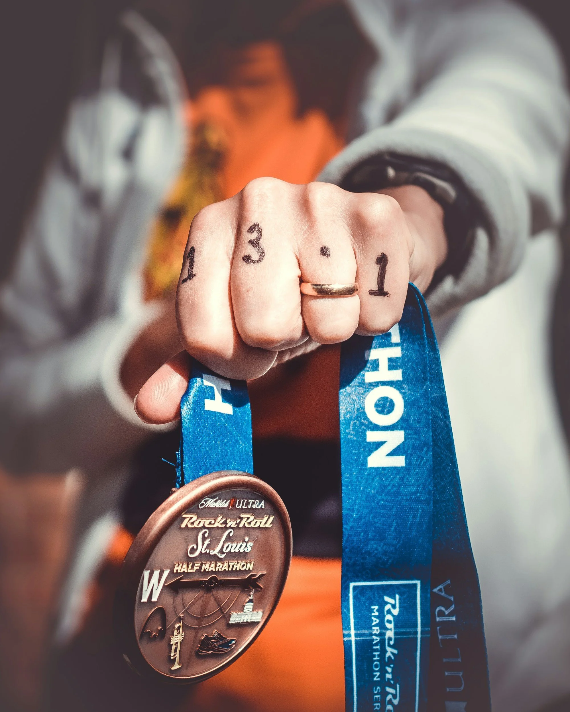 Woman holding half-marathon medal with 13.1 written on fingers representing performance identity