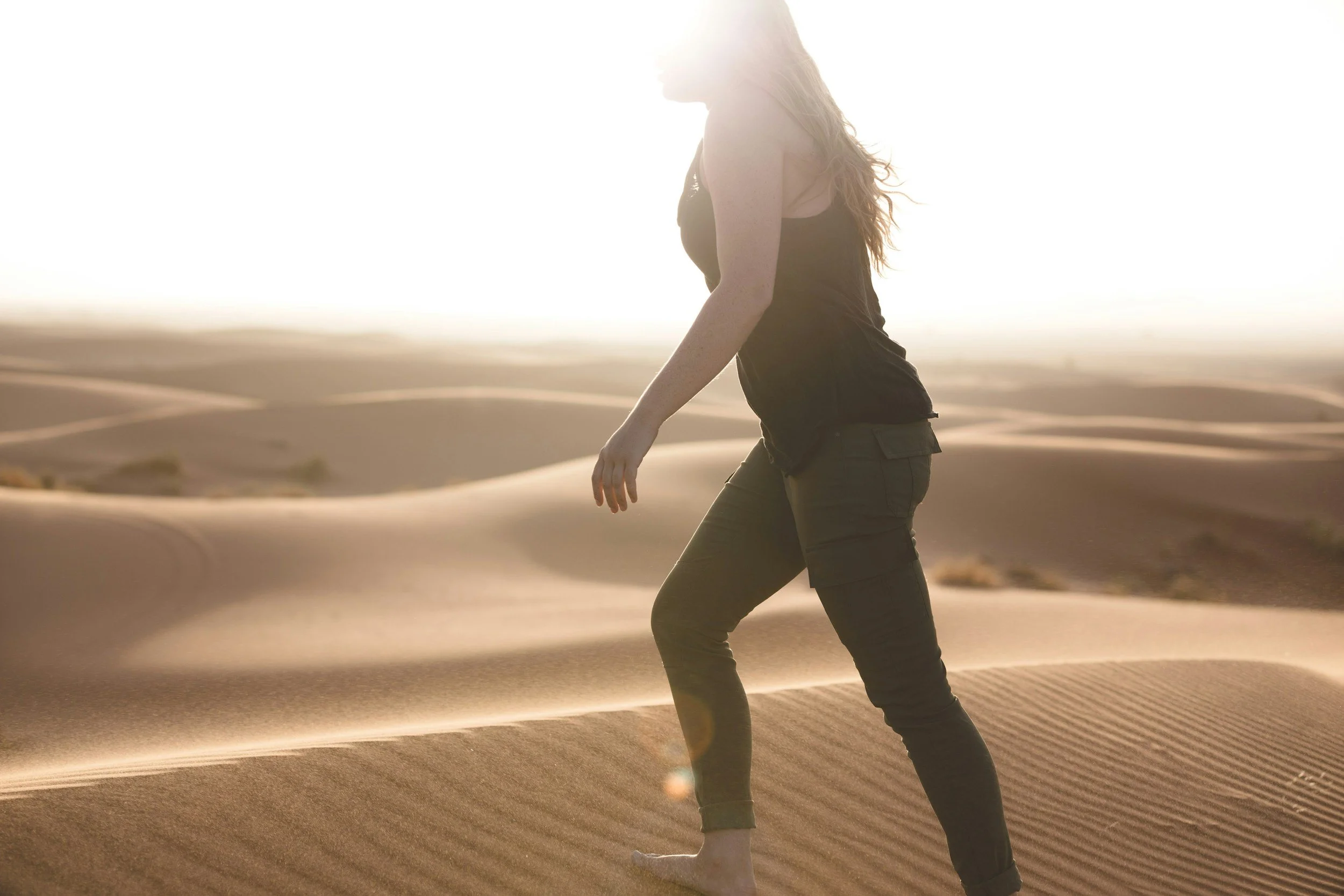 Middle aged blonde woman walking through desert sand representing purpose and forward motion in reclaiming identity in Christ during the empty nest season
