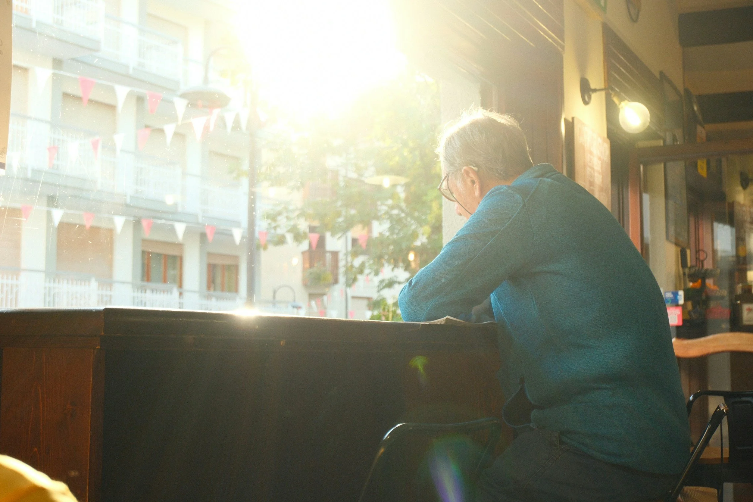 Older adult sitting alone by a café window in quiet reflection and emotional healing