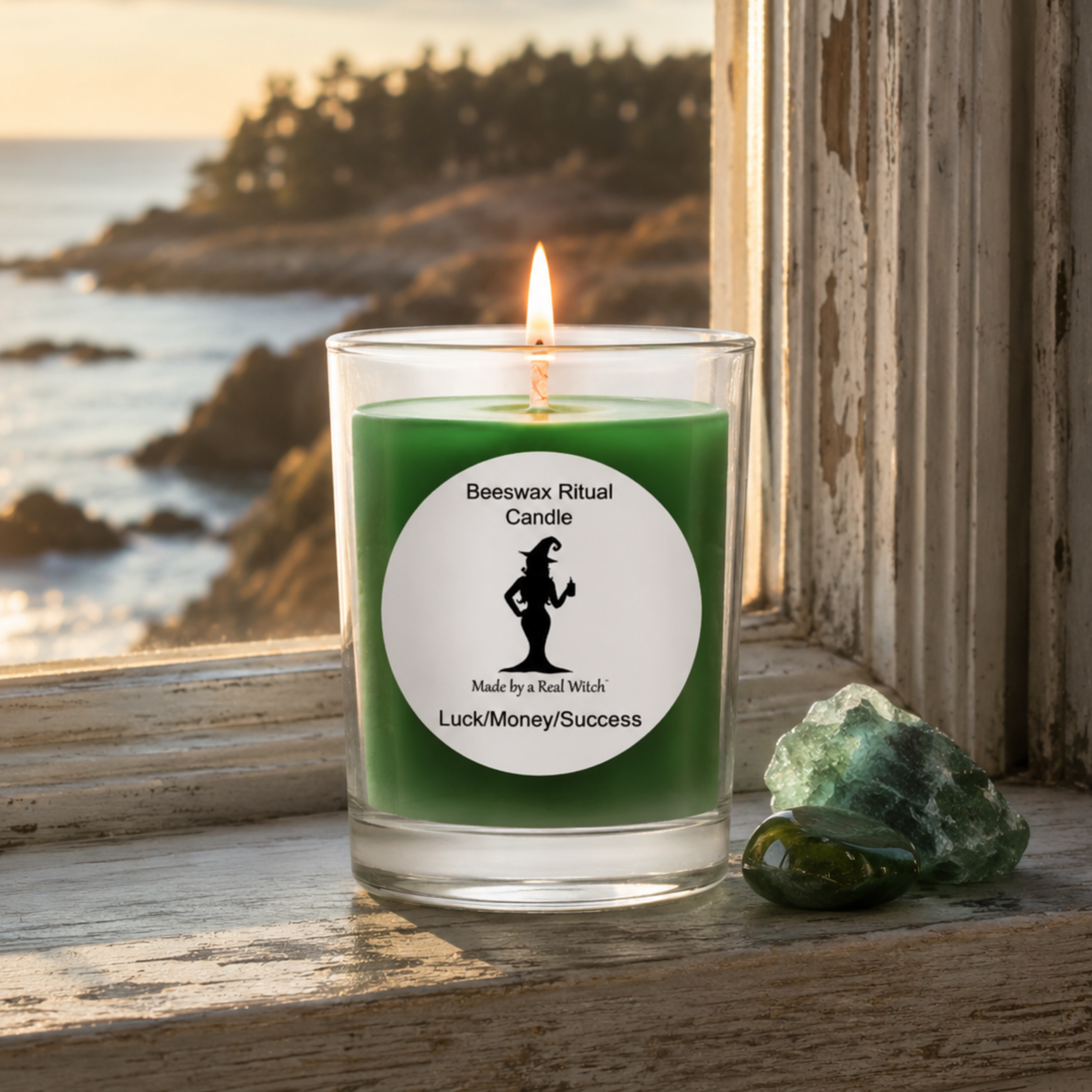 Green votive ritual candle softly burning on weathered windowsill overlooking the Atlantic coast.