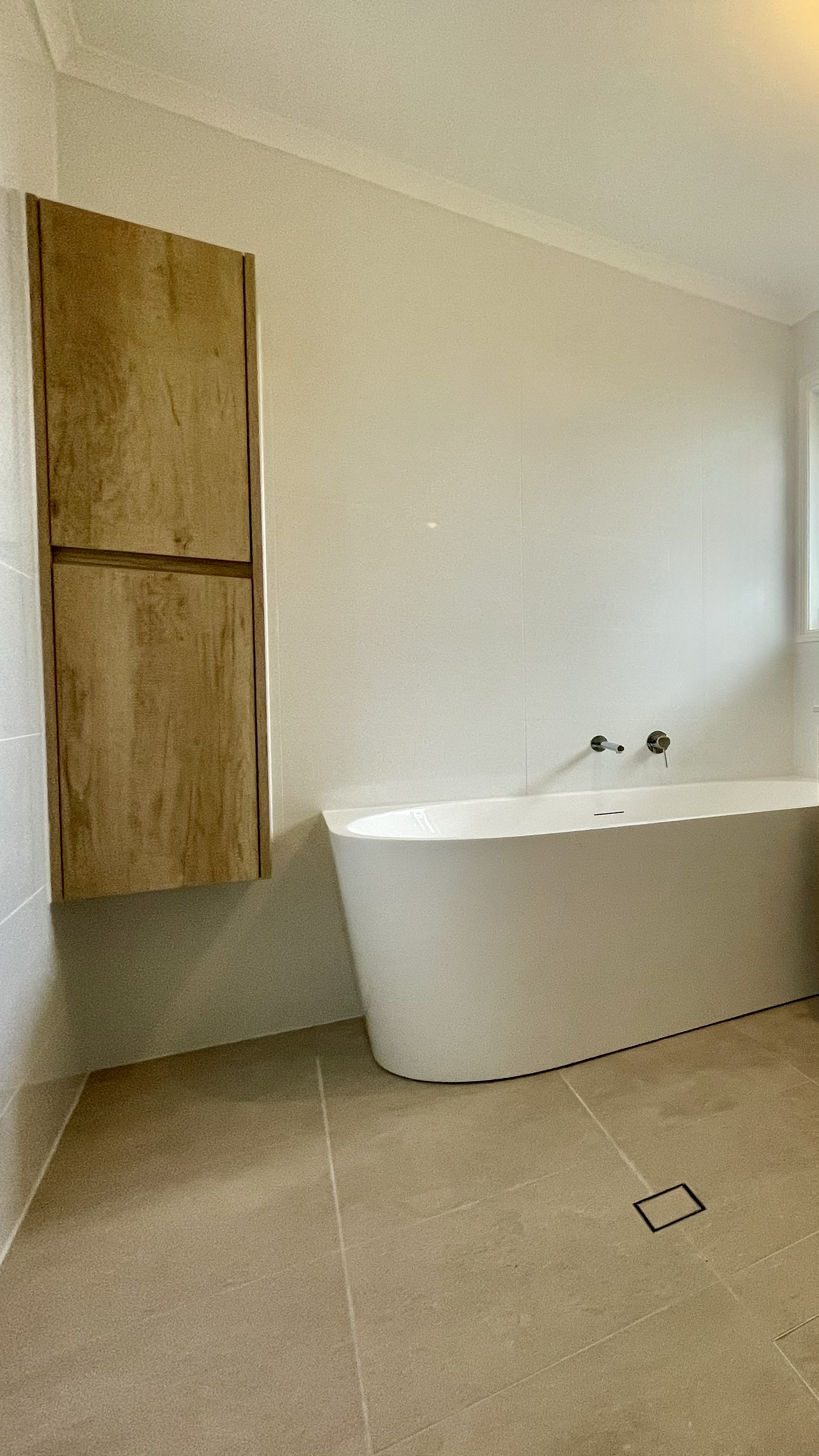 Bathroom renovation Rochedale South, Logan area, Brisbane Southside. Shower and modern vanity with round mirror, grey and white times. White bath tub, extra storage vertical cabinet.