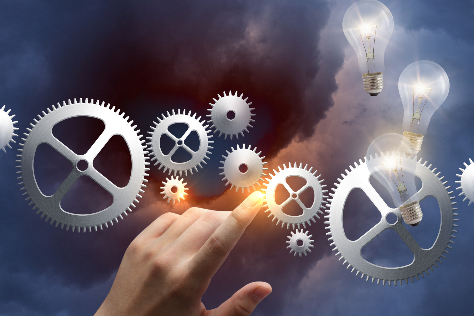 Hand touching digital gears and lightbulbs against a dark sky, symbolizing innovation and technology.
